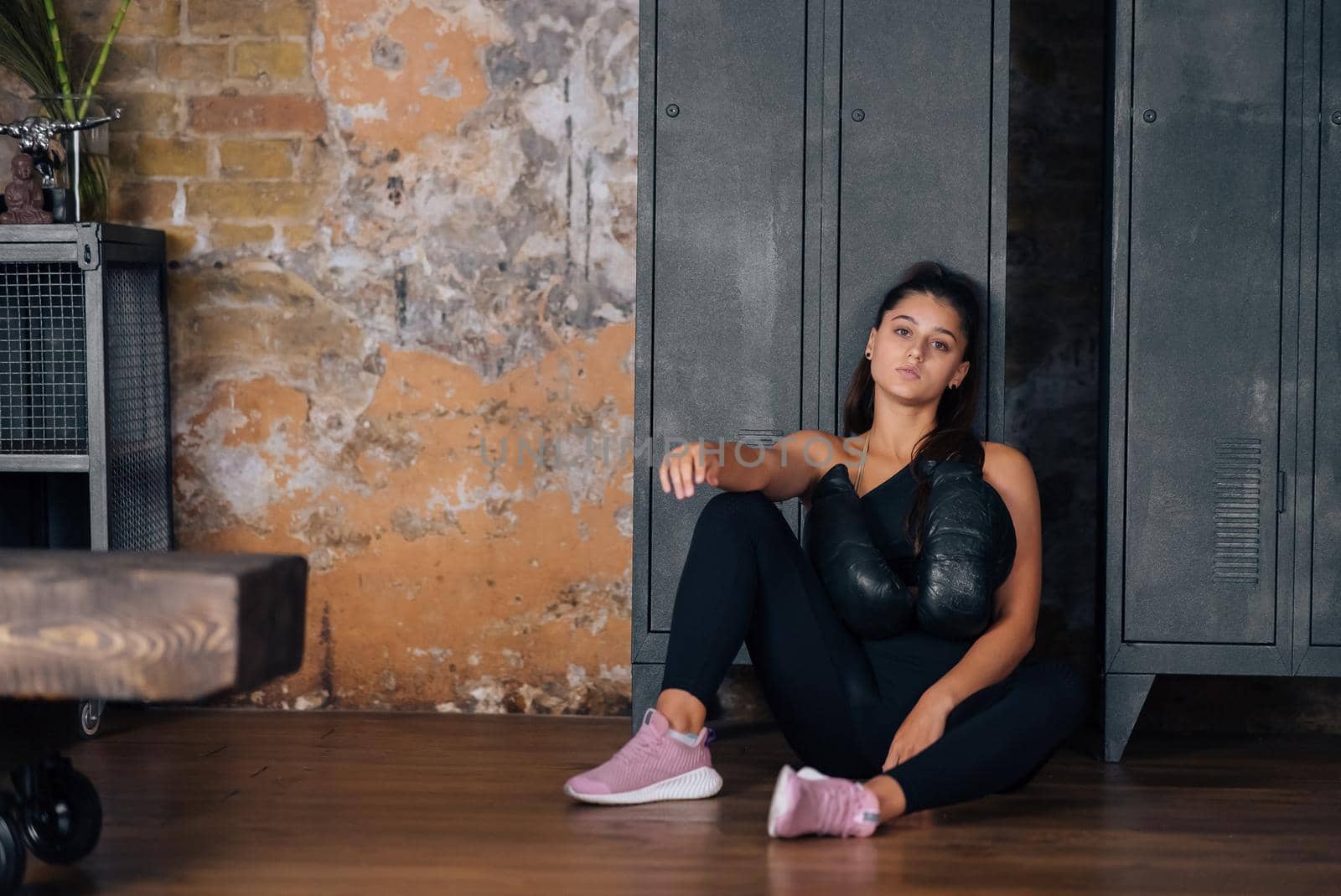 Sporty woman in sportswear posing on camera with boxing gloves. Sport and gym concept