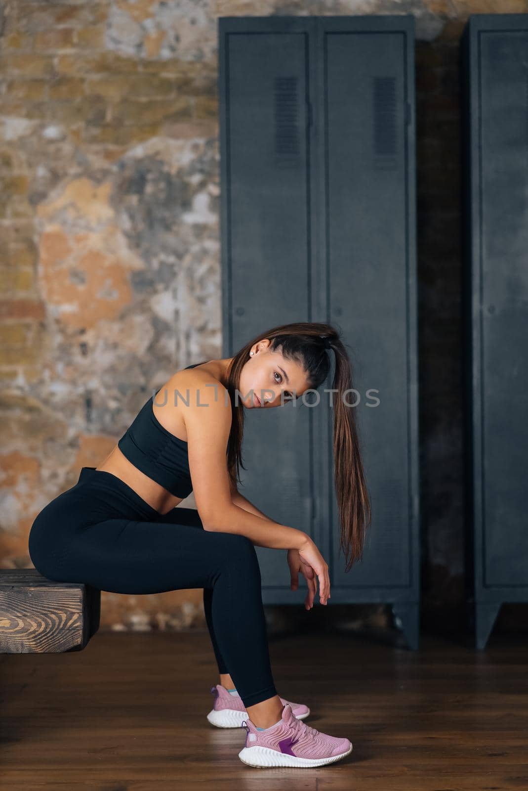 Sporty woman in sportswear resting on bench at fitness. Healthy people relax after workout. Sport and gym concept