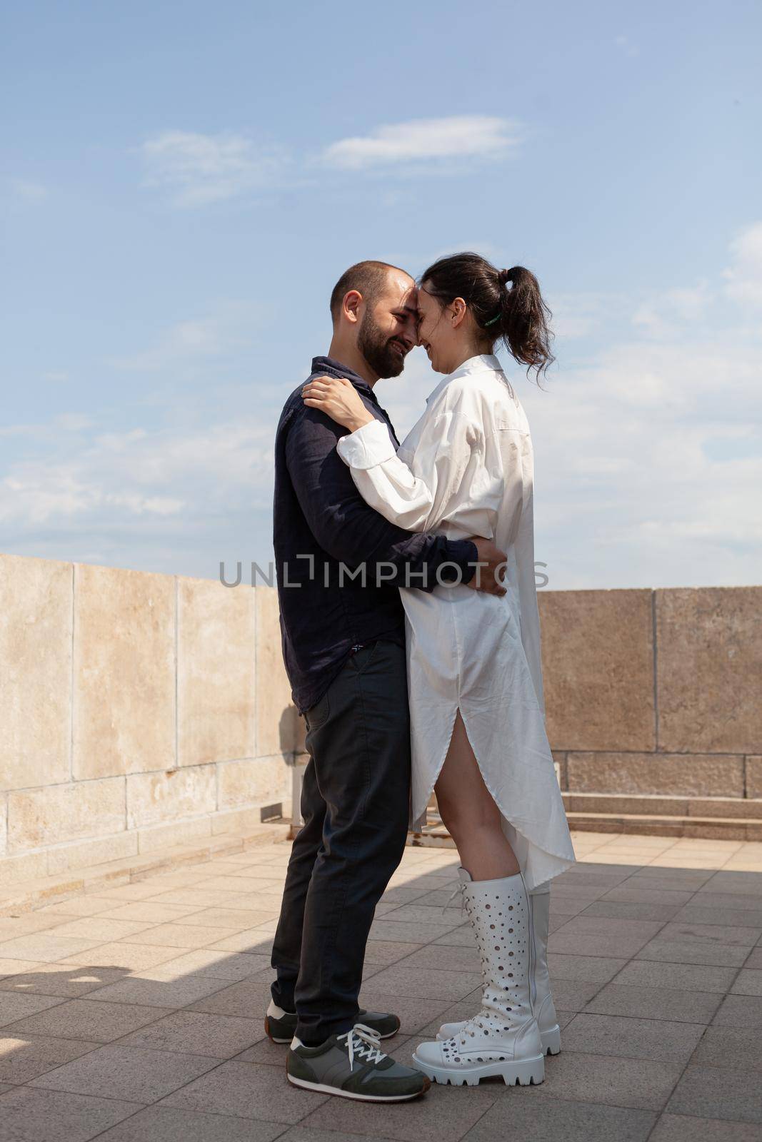 Happy romantic people hugging while standing on tower rooftop celebrating relationship anniversary during summer vacation. Panoramic skyline from tower observation point. Landscape of metropolitan city