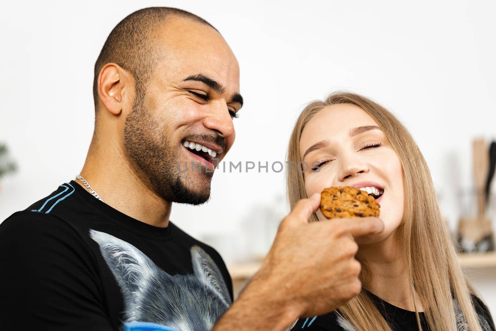 African american guy feeding his girlfriend with a cookie by Fabrikasimf