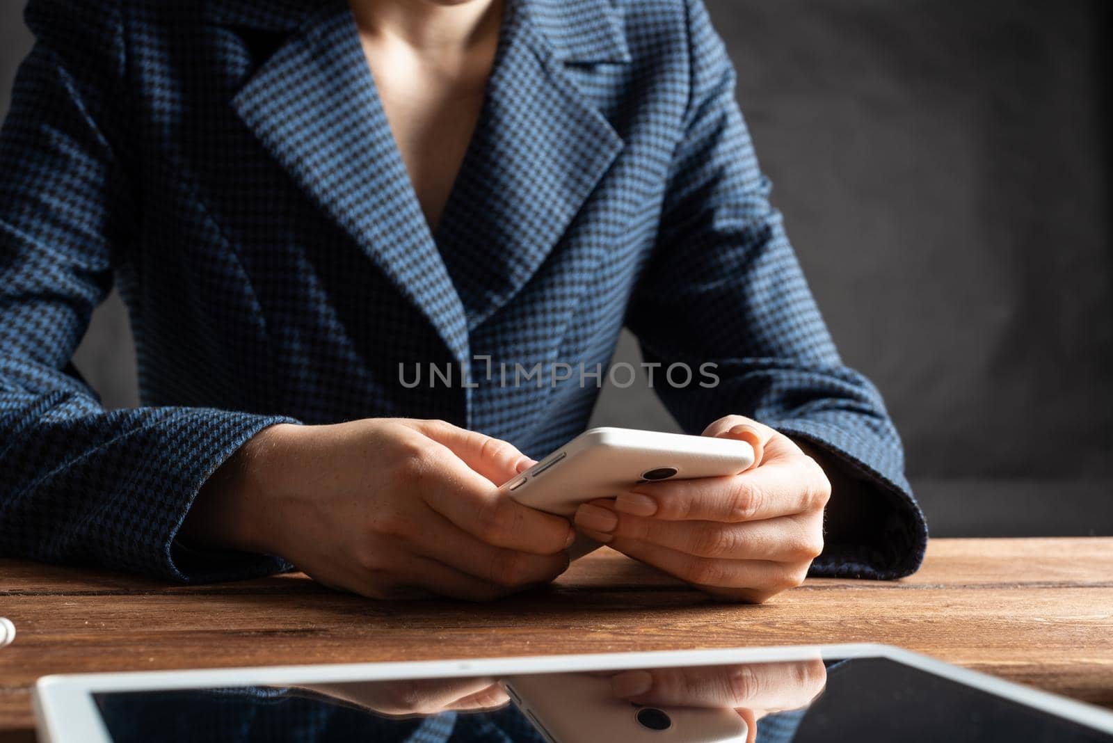 Businesswoman using mobile phone at desk. Close up woman hands and tablet computer. Mobile communication concept with chatting woman. Digital technology in strategy planning and company management