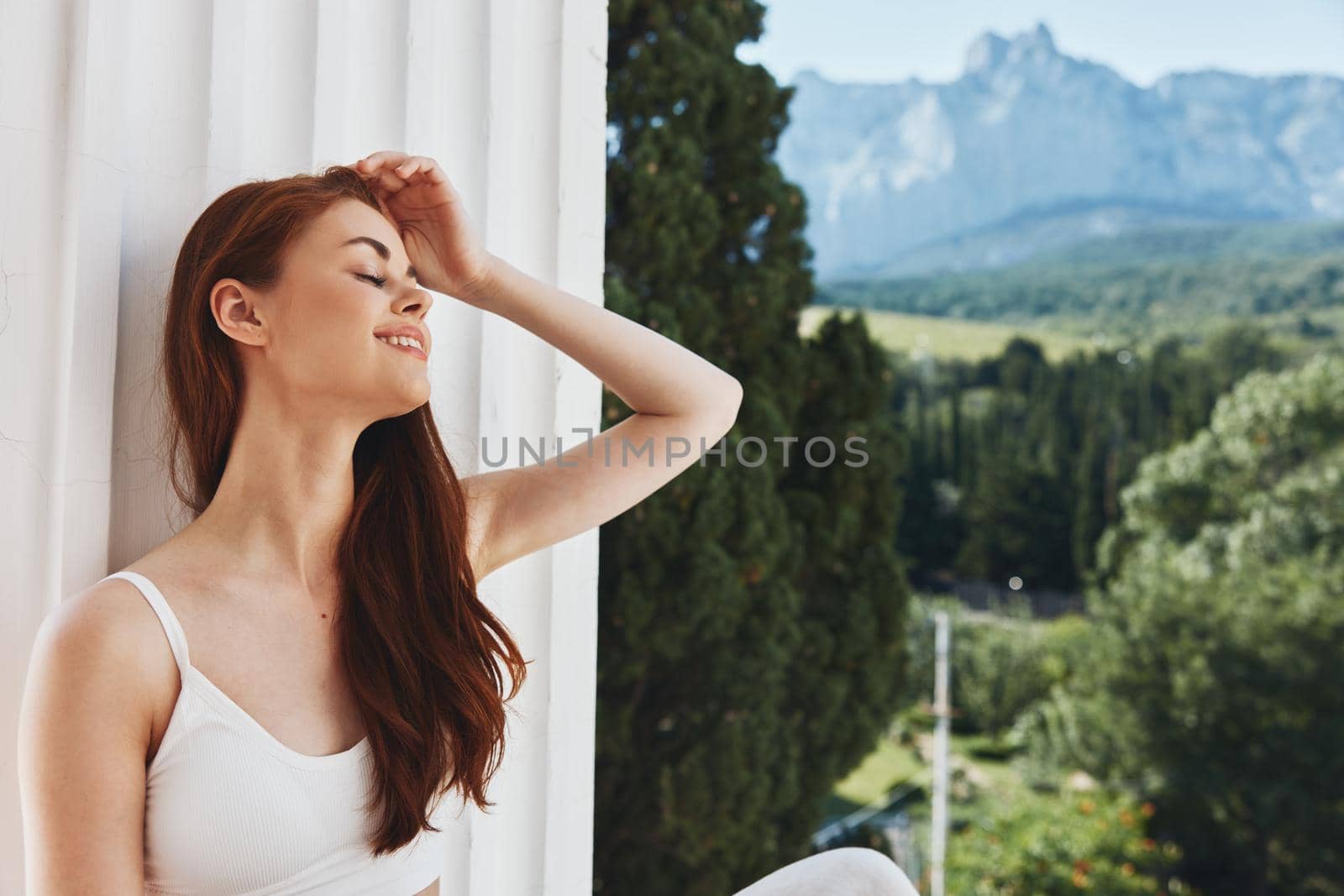 beautiful woman with long hair on an open balcony Green nature summer day Mountain View. High quality photo