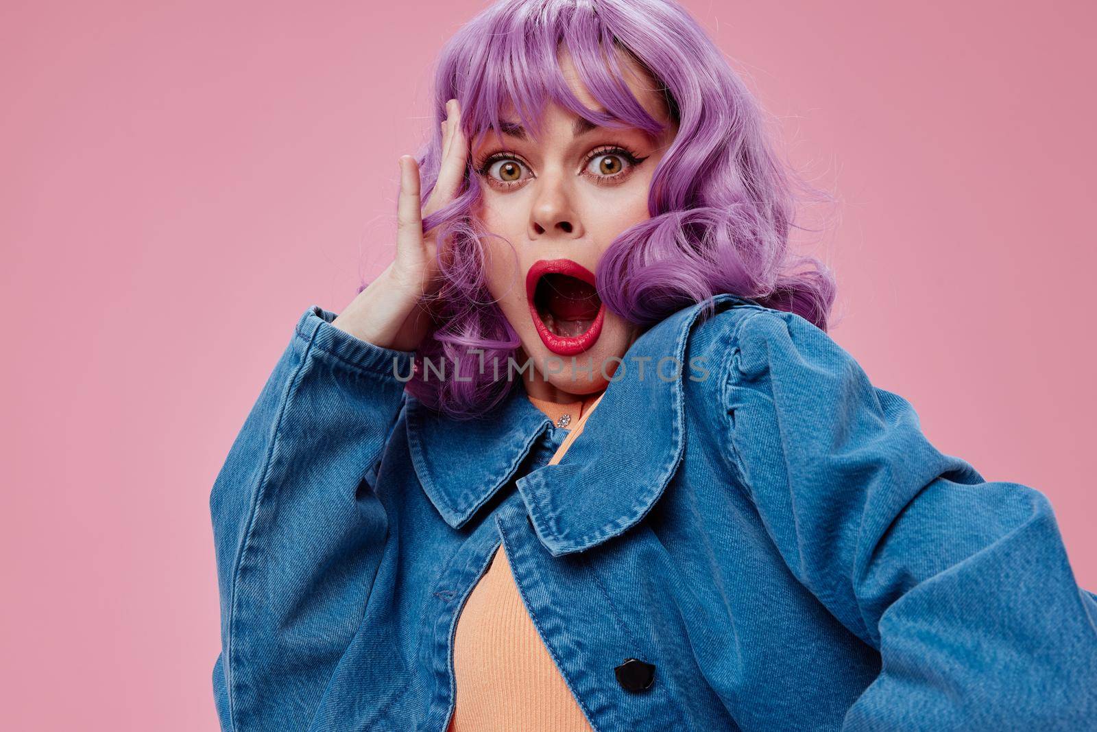 Pretty young female wavy purple hair blue jacket emotions fun pink background unaltered. High quality photo