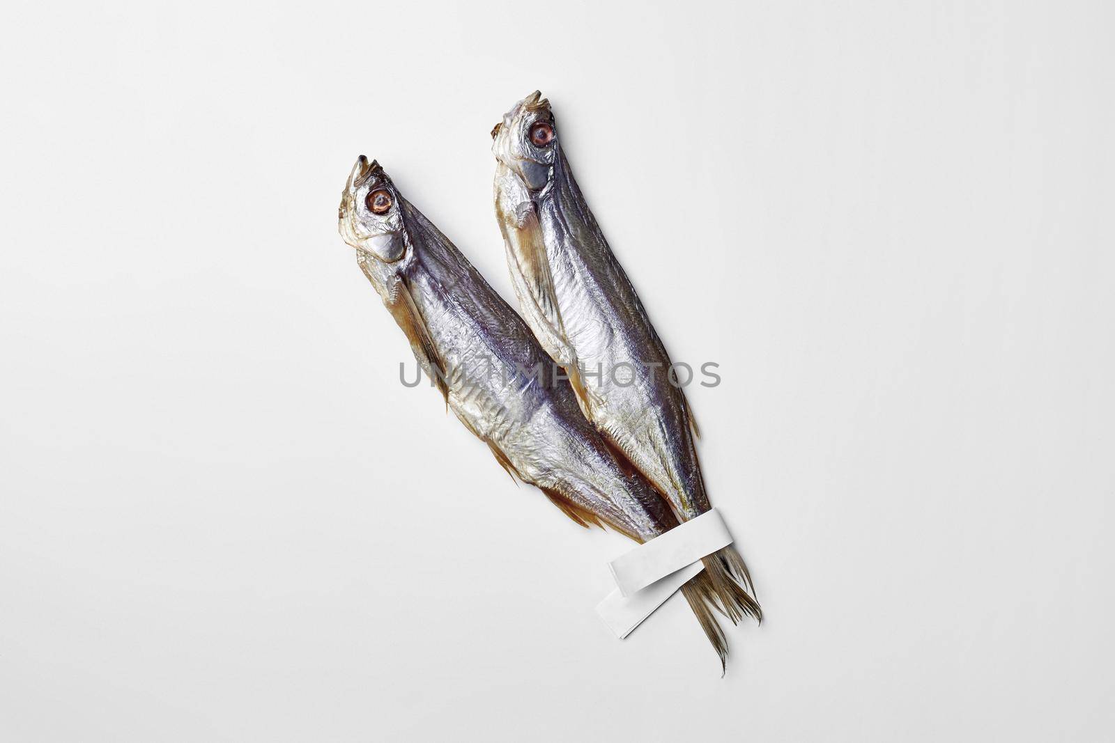 Two salted air-dried sabrefish with paper labels on tails isolated on white background with copyspace. Popular fish appetizer concept