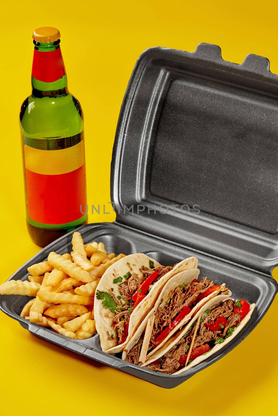 Birria tacos in takeaway container with fries and bottle of drink on yellow background by nazarovsergey