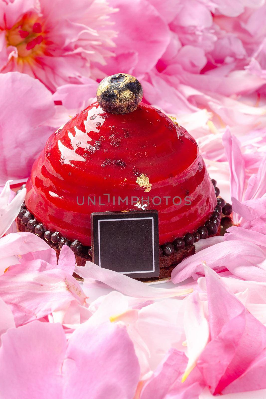 Dessert with cherry mousse on chocolate sponge cake covered with berry confit among pink peony petals by nazarovsergey