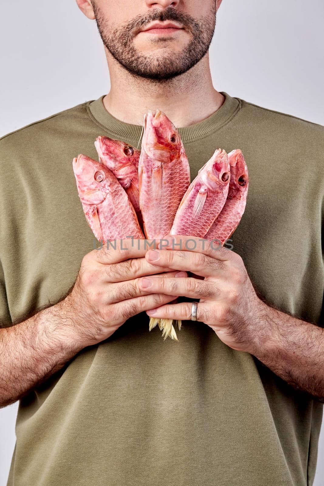 Bearded man holding bunch of air-dried red mullets in hands by nazarovsergey