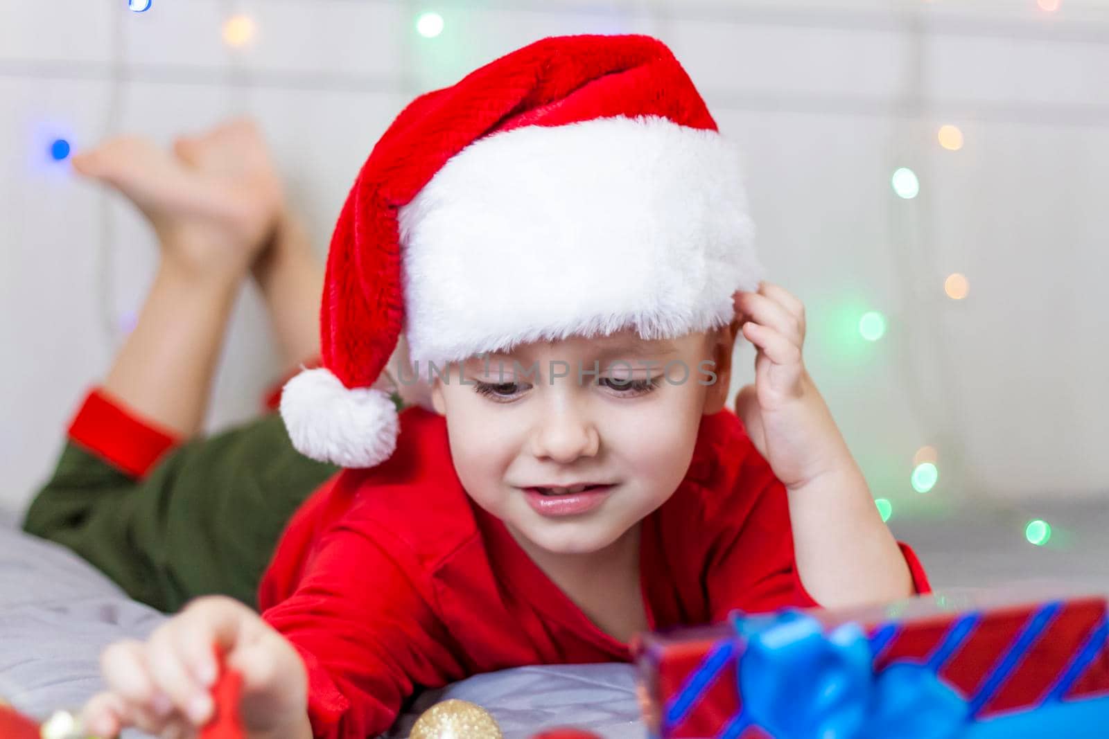 Portrait of a cute boy in a Santa Claus hat. Funny smiling child. Gifts, toys, joy, celebration. Christmas concert.