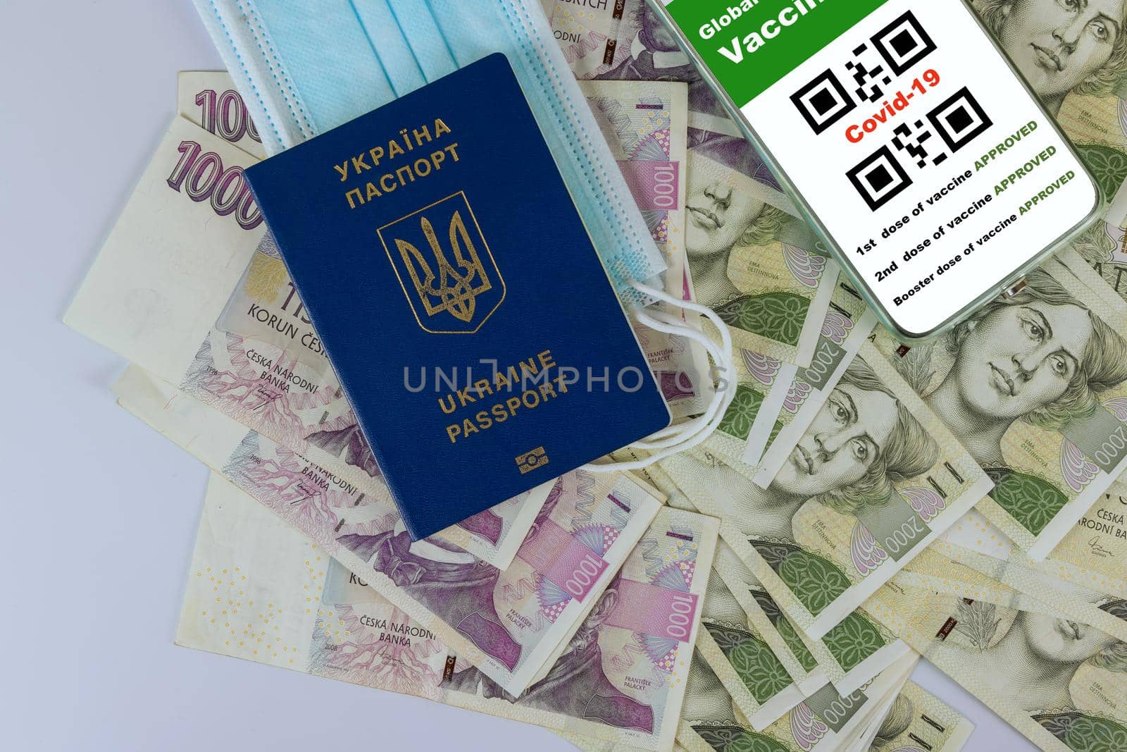 New normal travel Ukrainian passport of tourist to Czech republic with smartphone display on vaccinated COVID-19 coronavirus certificate, immunity vaccine passport of money Czech Koruna
