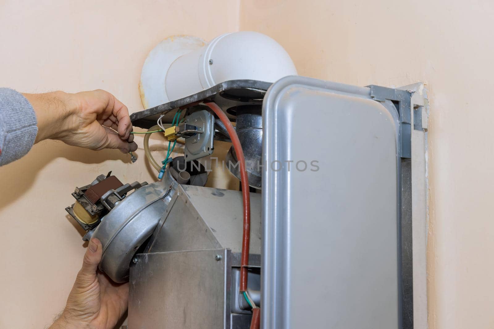 Professional plumber servicing a central heating system boiler by ungvar
