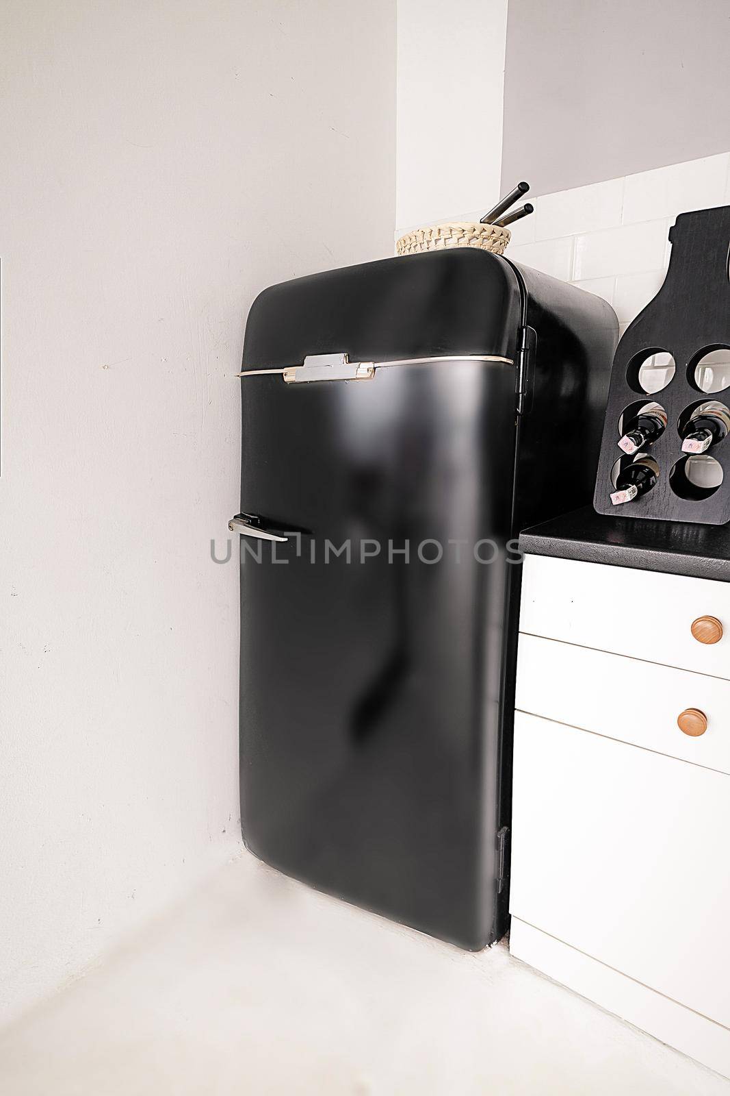 Glossy Stylish Fridge in Retro Style in White Kitchen. Black Refrigerator in Vintage Style on White Background. Close-up. High quality photo