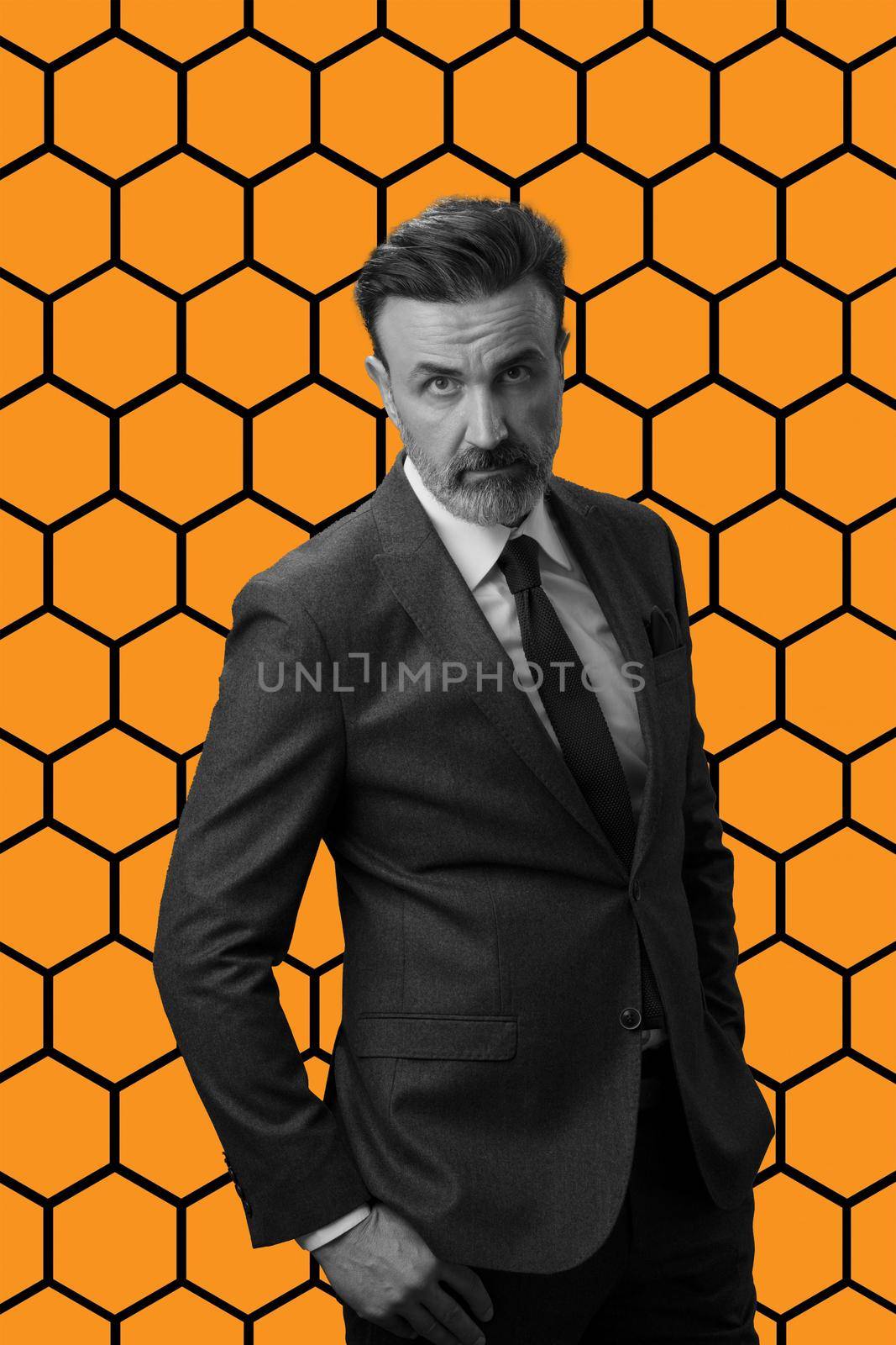 Black and white portrait of a stylish elegant senior businessman with a beard and casual business clothes against retro colorful pattern design background gesturing with hands by dotshock