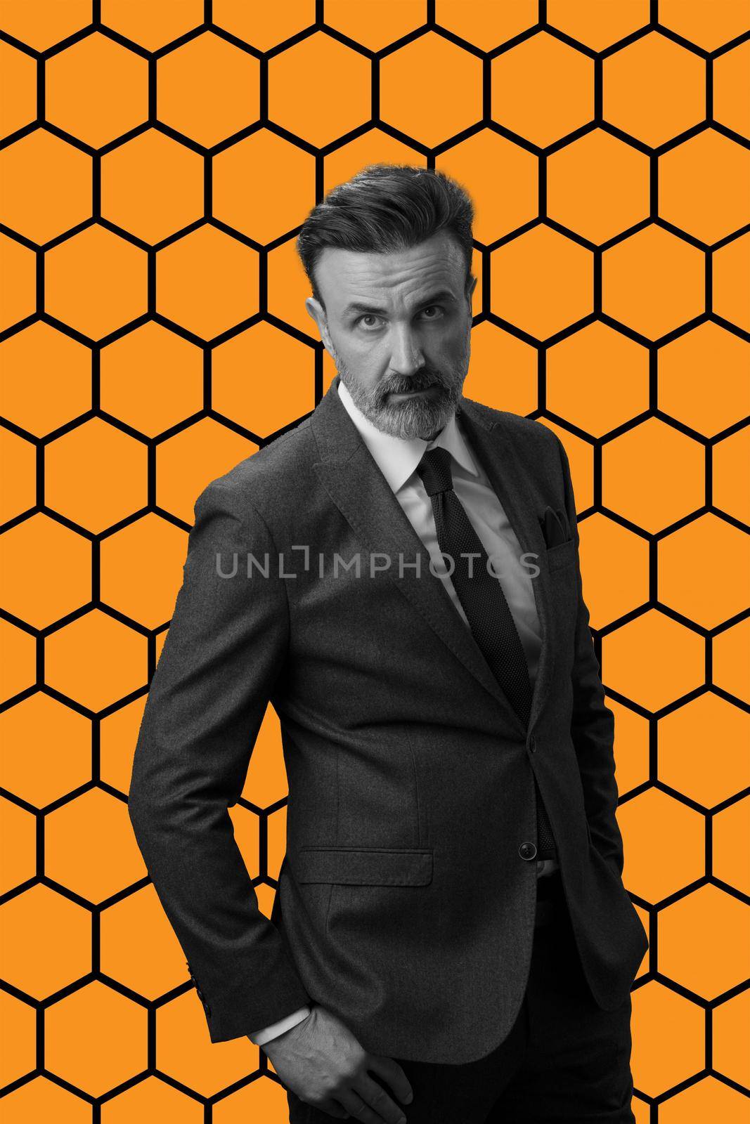 Black and white portrait of a stylish elegant senior businessman with a beard and casual business clothes against retro colorful pattern design background gesturing with hands. High quality photo