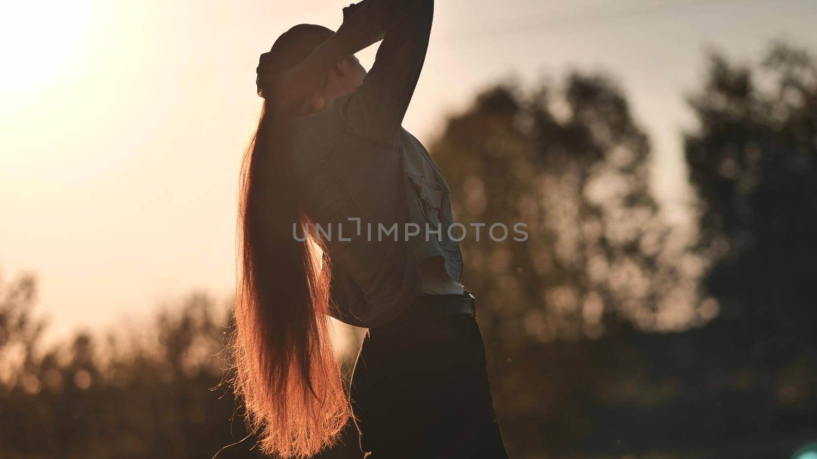 Silhouette of a girl with long hair at sunset. by DovidPro