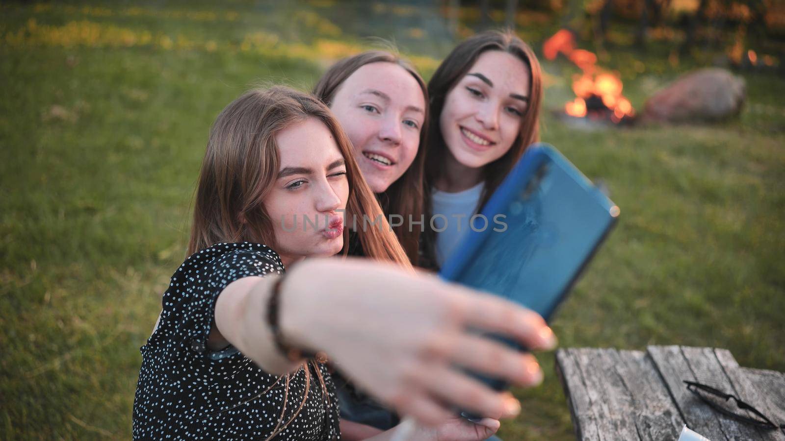 Three schoolgirls make selfies using a smartphone