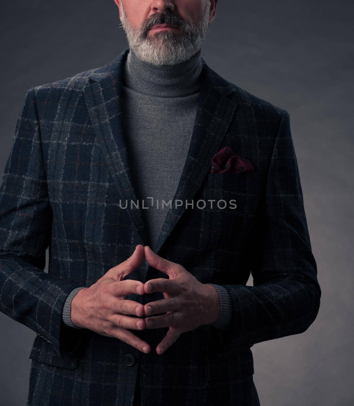 Portrait of a successful stylish elegant senior businessman with a grey beard and casual business clothes confident in photo studio isolated on dark background gesturing with hands. High-quality photo