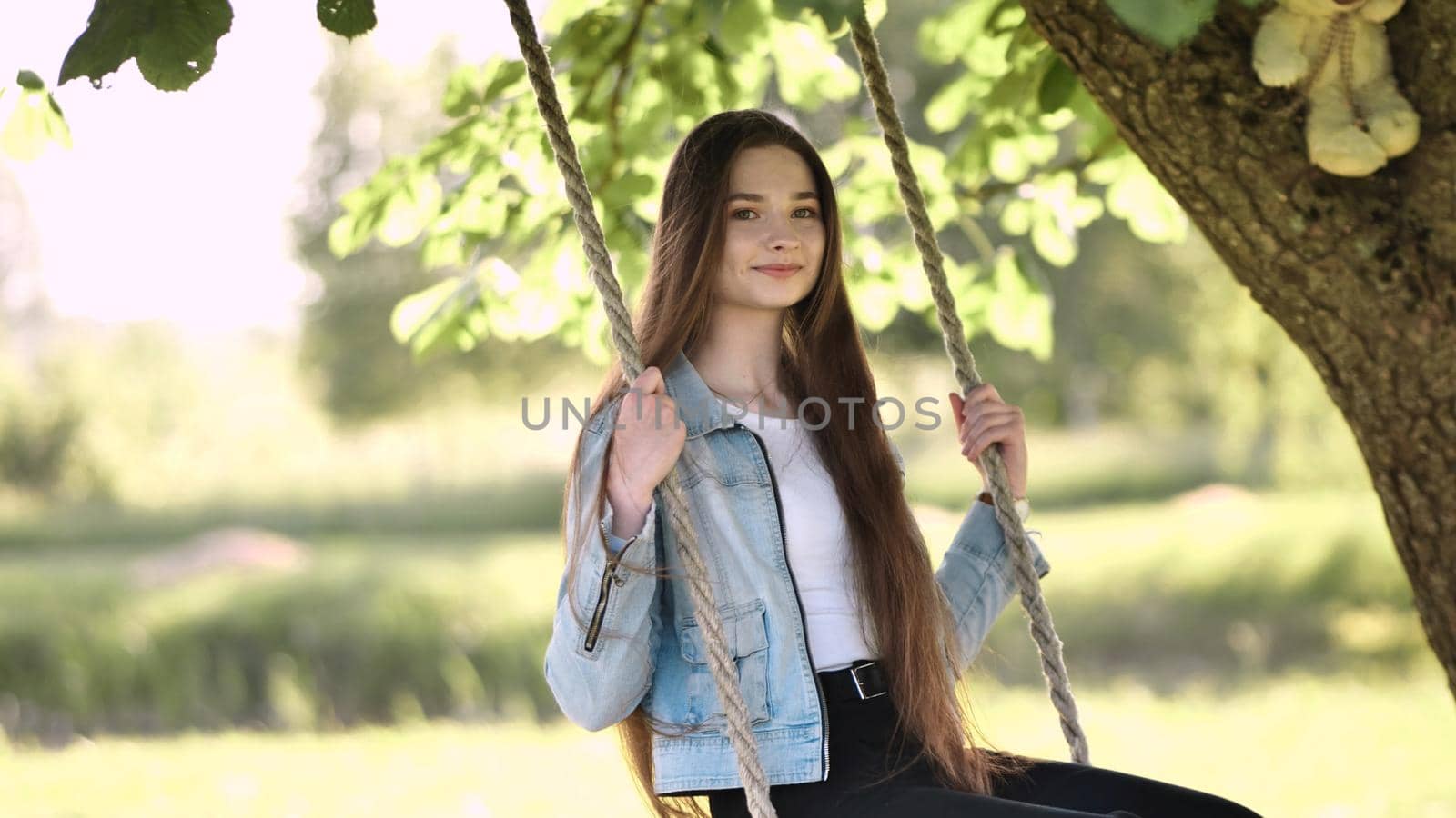 Young beautiful long-haired girl on a rope swing. by DovidPro