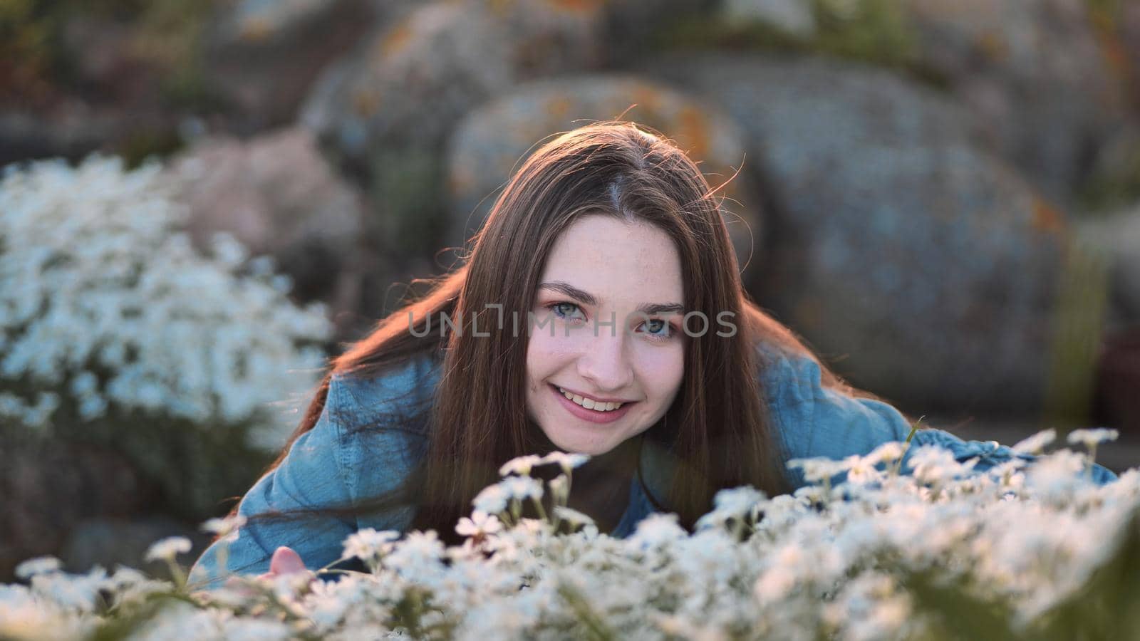 Long-haired girl sniffs white flowers and smiles. by DovidPro