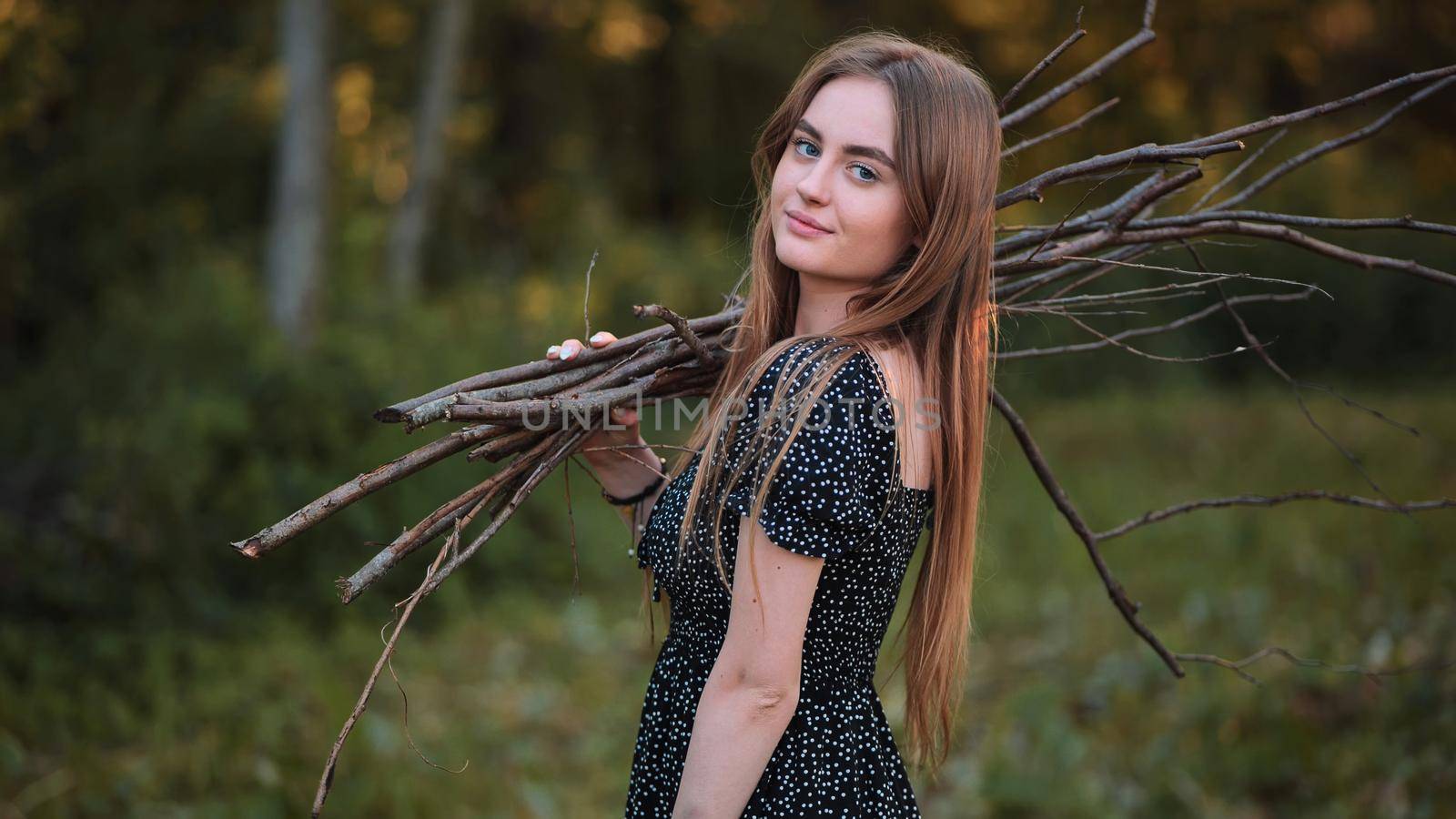 Young girl posing with brushwood for a fire on a picnic. by DovidPro