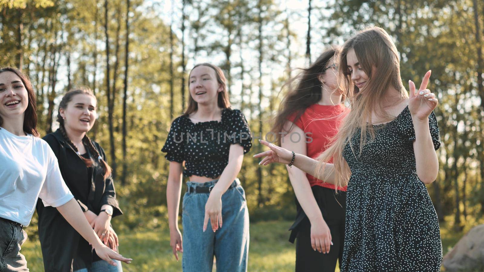 Joyful girls are dancing on a picnic near the forest