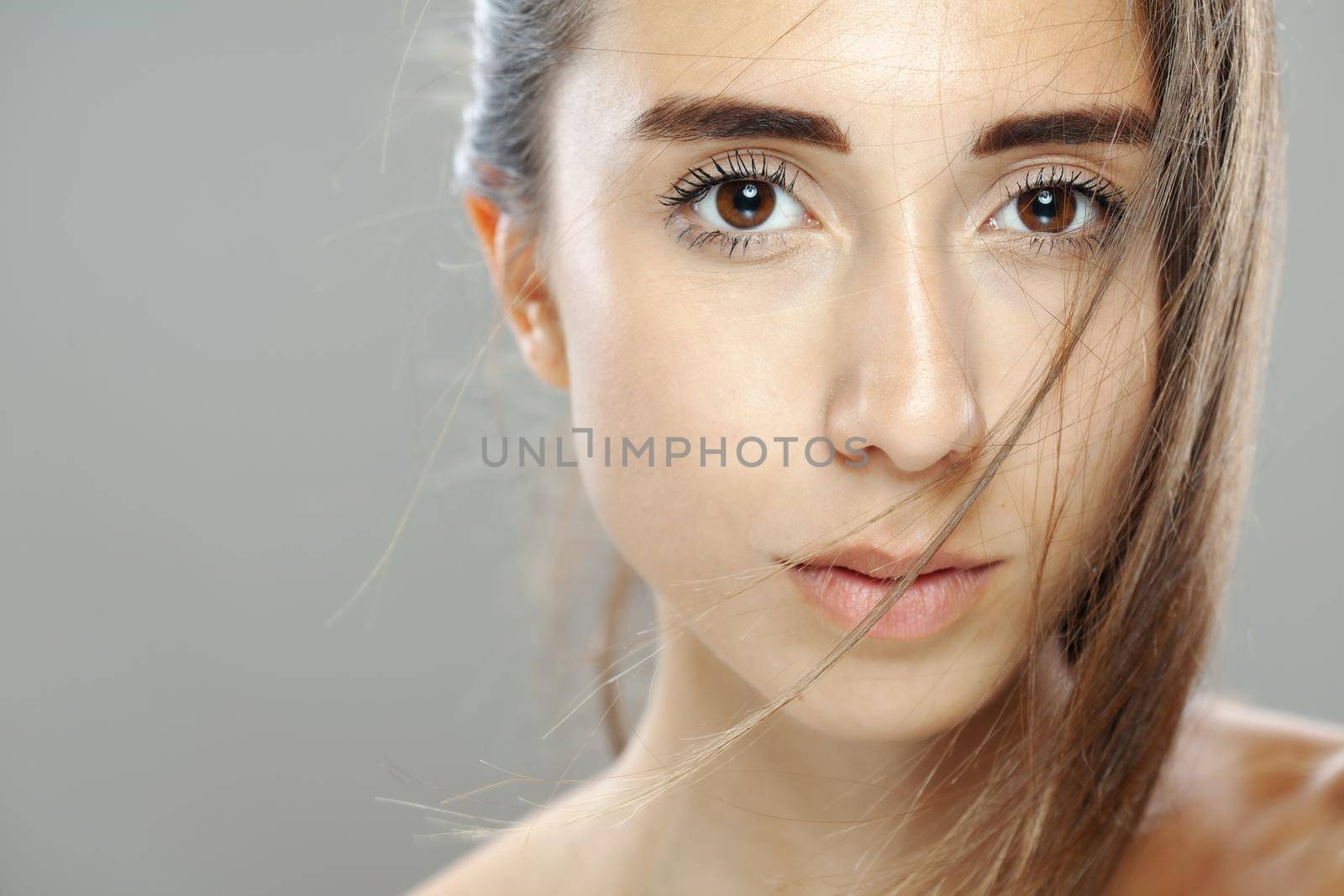 Beautiful brunette girl studio portrait. Serious face expression.