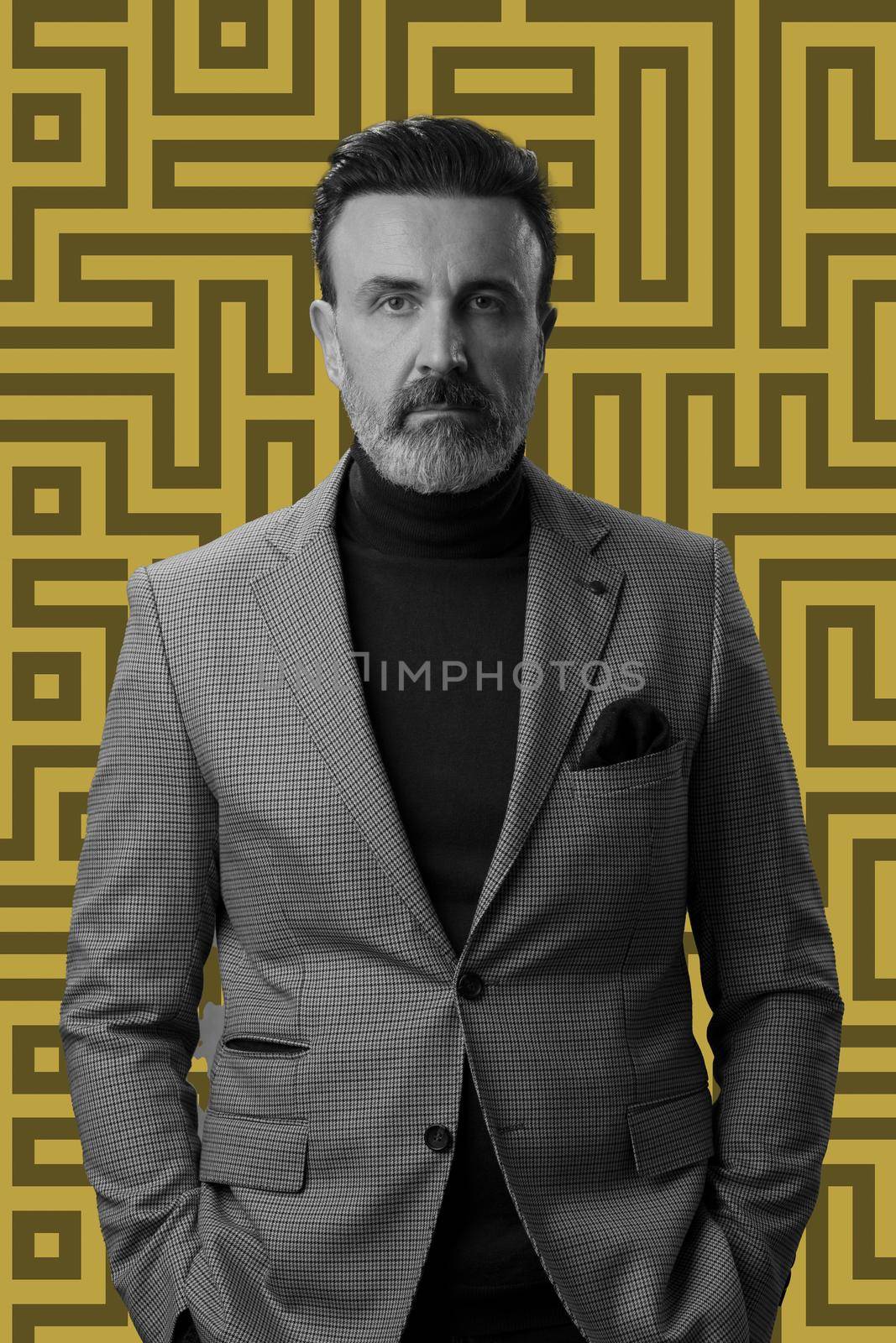 Black and white portrait of a stylish elegant senior businessman with a beard and casual business clothes against retro colorful pattern design background gesturing with hands by dotshock