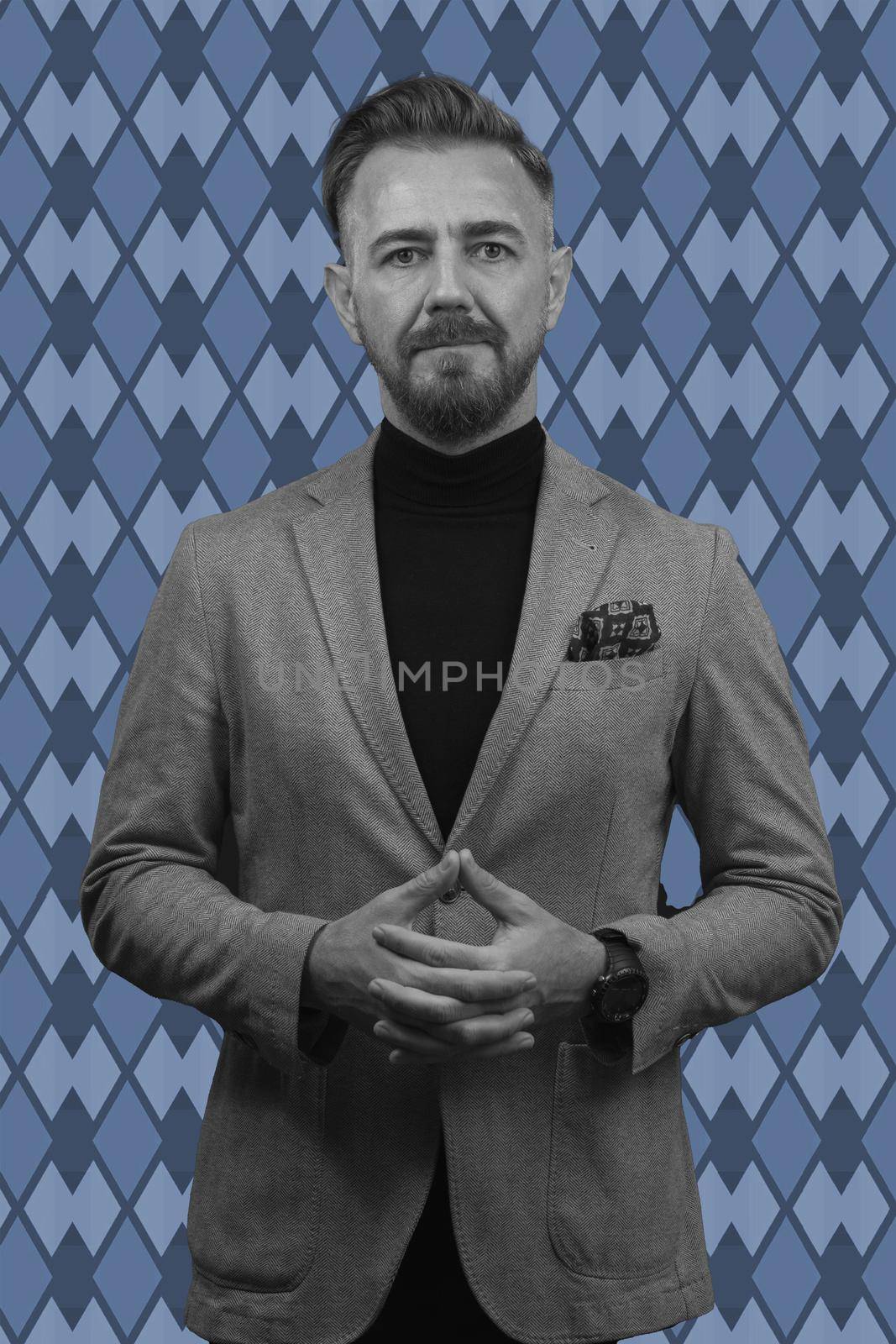 Black and white portrait of a stylish elegant senior businessman with a beard and casual business clothes against retro colorful pattern design background gesturing with hands by dotshock