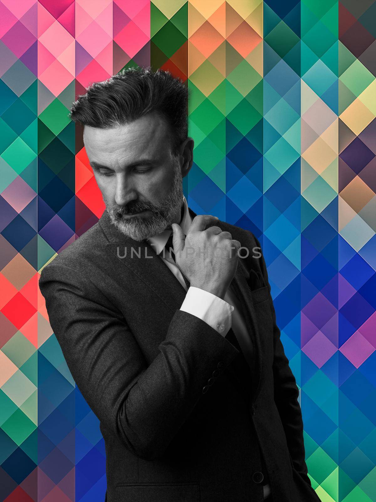 Black and white portrait of a stylish elegant senior businessman with a beard and casual business clothes against retro colorful pattern design background gesturing with hands. High quality photo