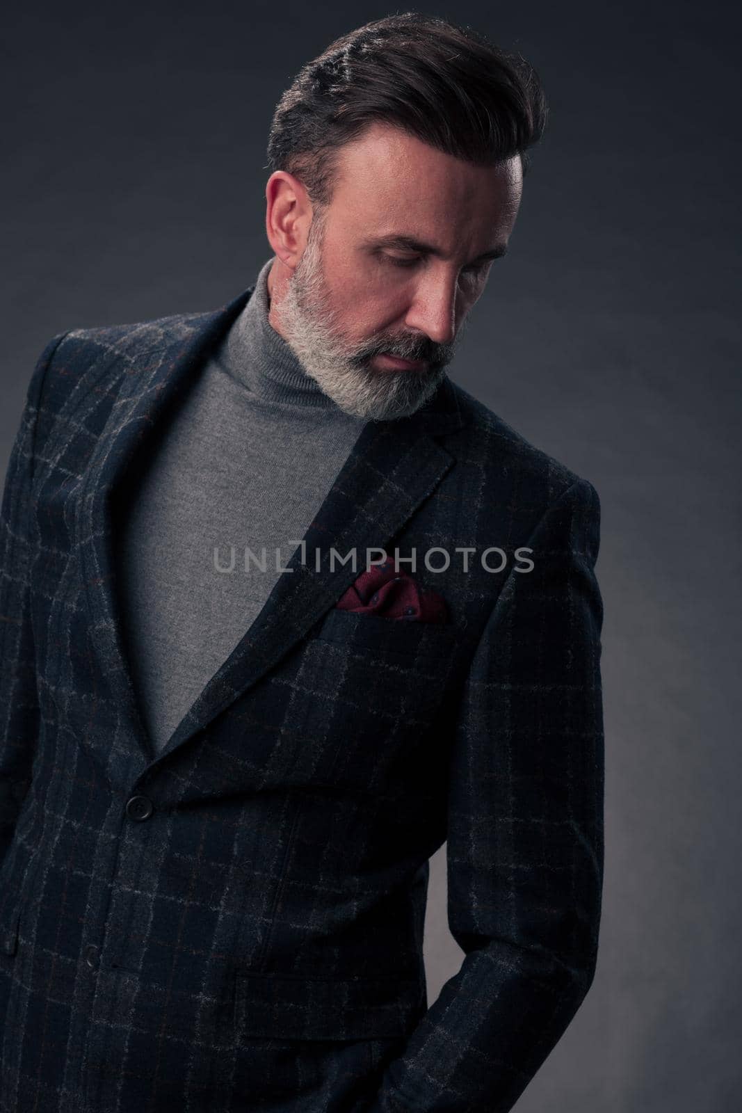 Portrait of a stylish elegant senior businessman with a beard and casual business clothes in photo studio isolated on dark background gesturing with hands by dotshock