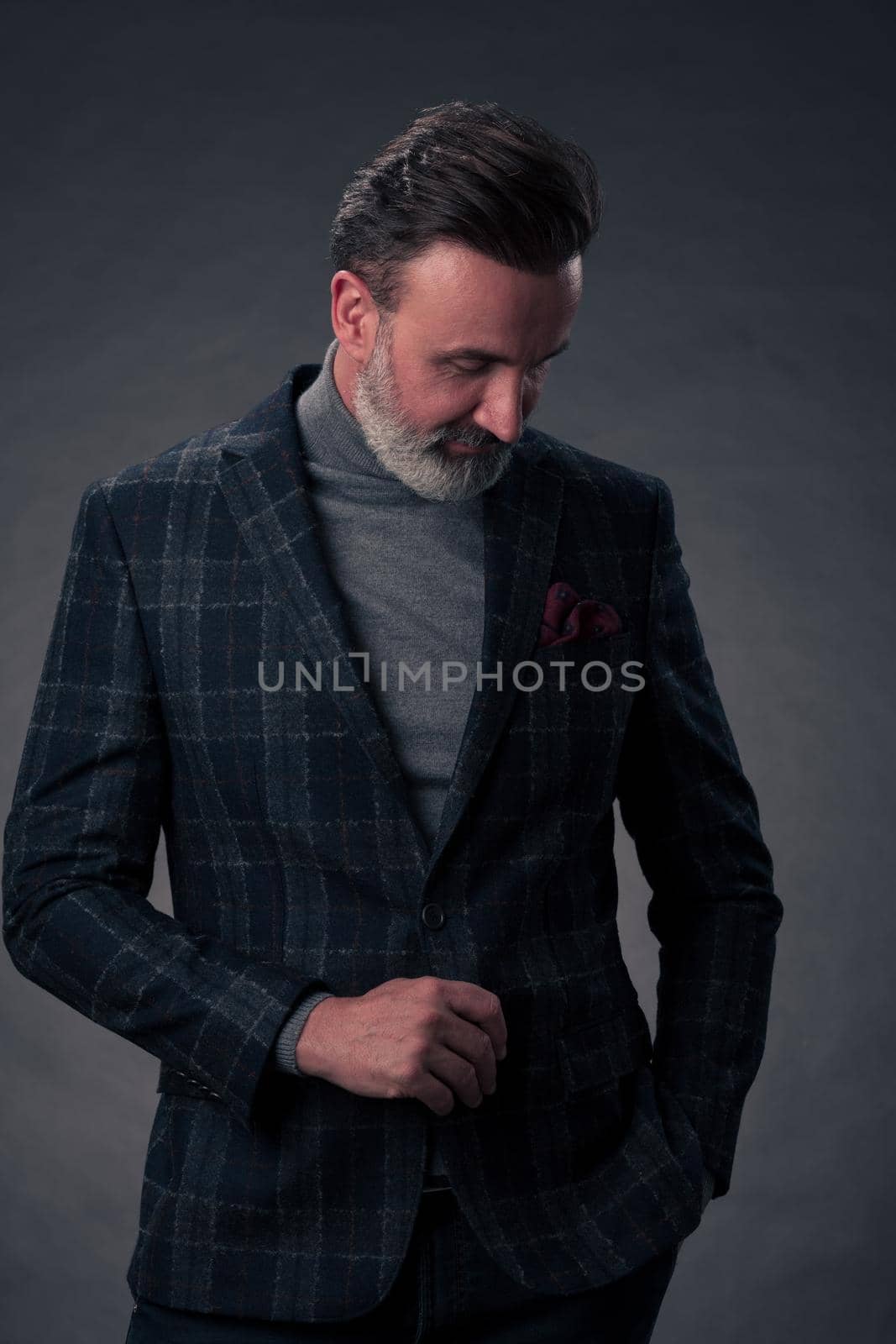 Portrait of a stylish elegant senior businessman with a beard and casual business clothes in photo studio isolated on dark background gesturing with hands by dotshock