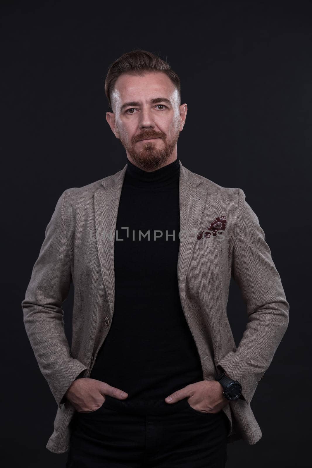 portrait of a stylish elegant businessman looking at camera in photo studio on dark background with hard light by dotshock