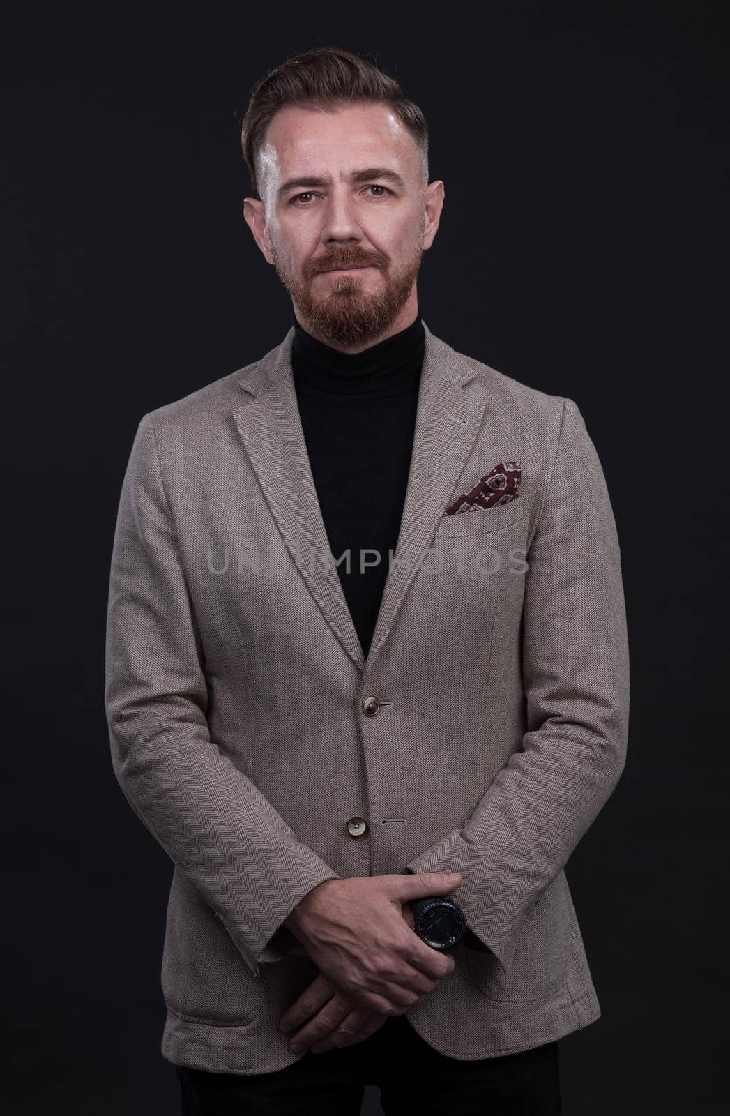 portrait of a stylish elegant businessman looking at camera in photo studio on dark background with hard light by dotshock