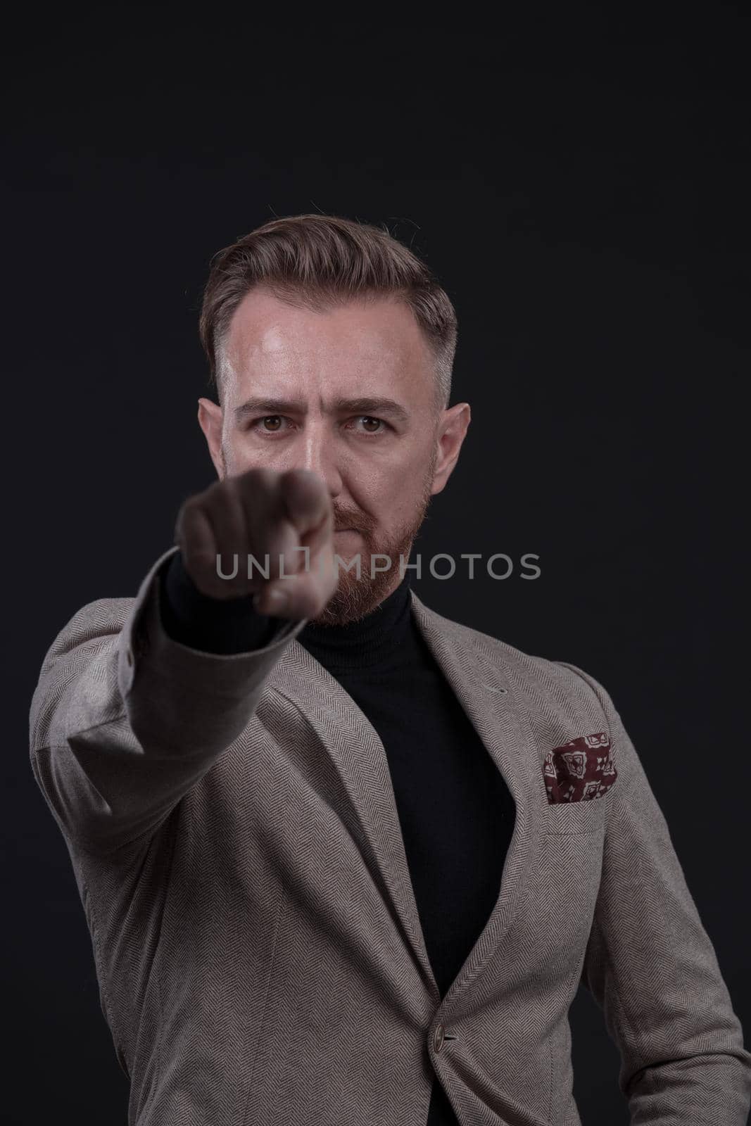 Portrait of a stylish elegant senior businessman with a beard and casual business clothes in photo studio isolated on dark background gesturing with hands. High quality photo