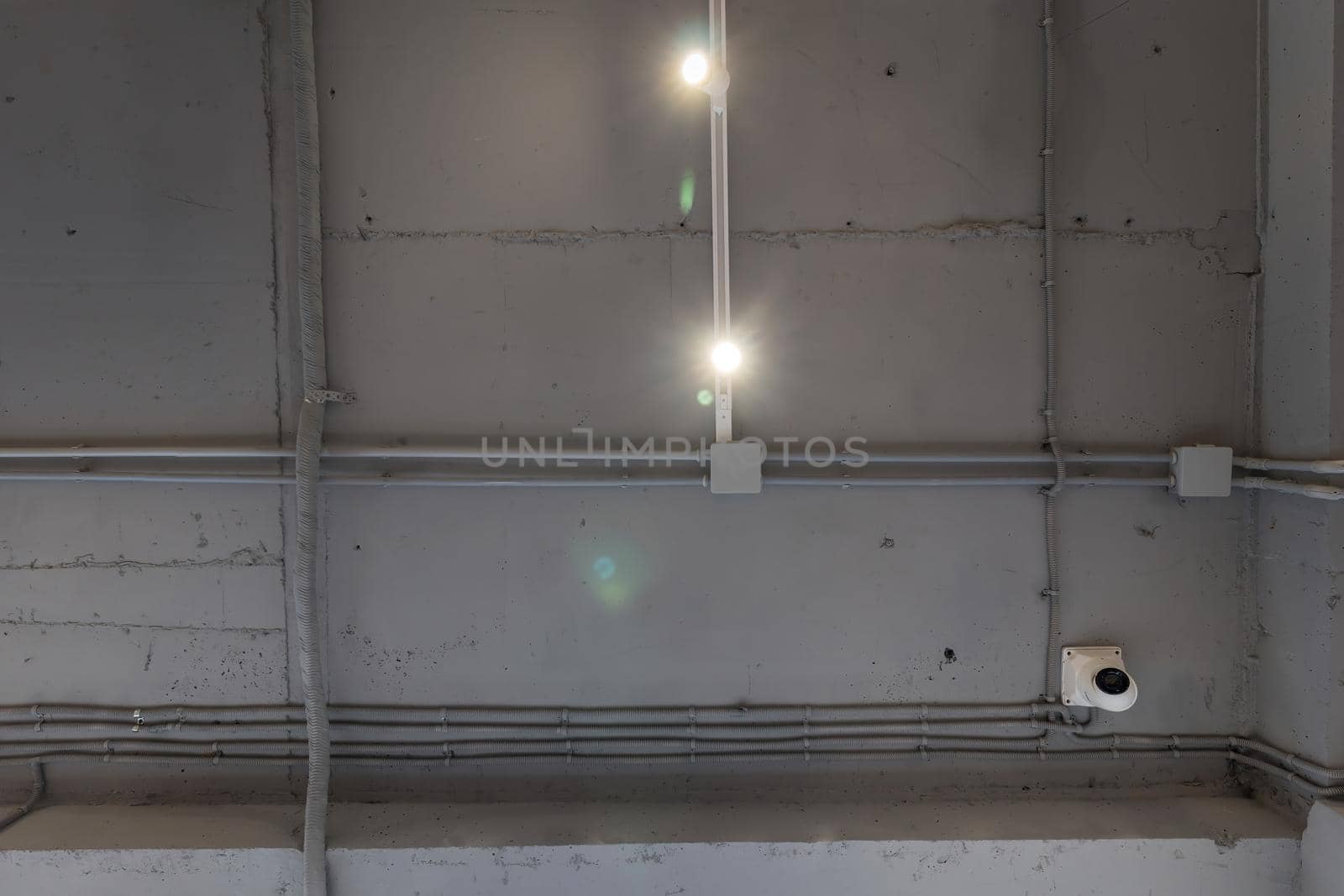 Abstract loft interior of concrete grey ceiling with air ventilation and security camera. Interior architecture and ceiling design of industrial loft building decorated with modern lamps by panophotograph