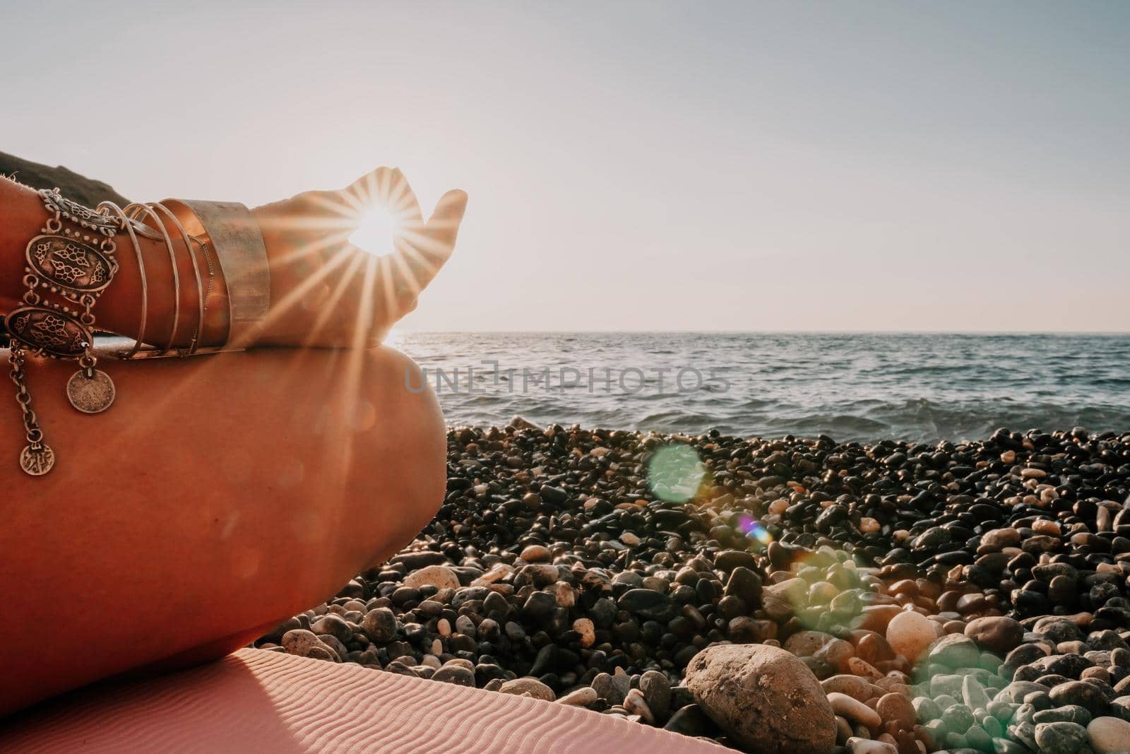 Young woman in swimsuit with long hair practicing stretching outdoors on yoga mat by the sea on a sunny day. Women's yoga fitness pilates routine. Healthy lifestyle, harmony and meditation concept.