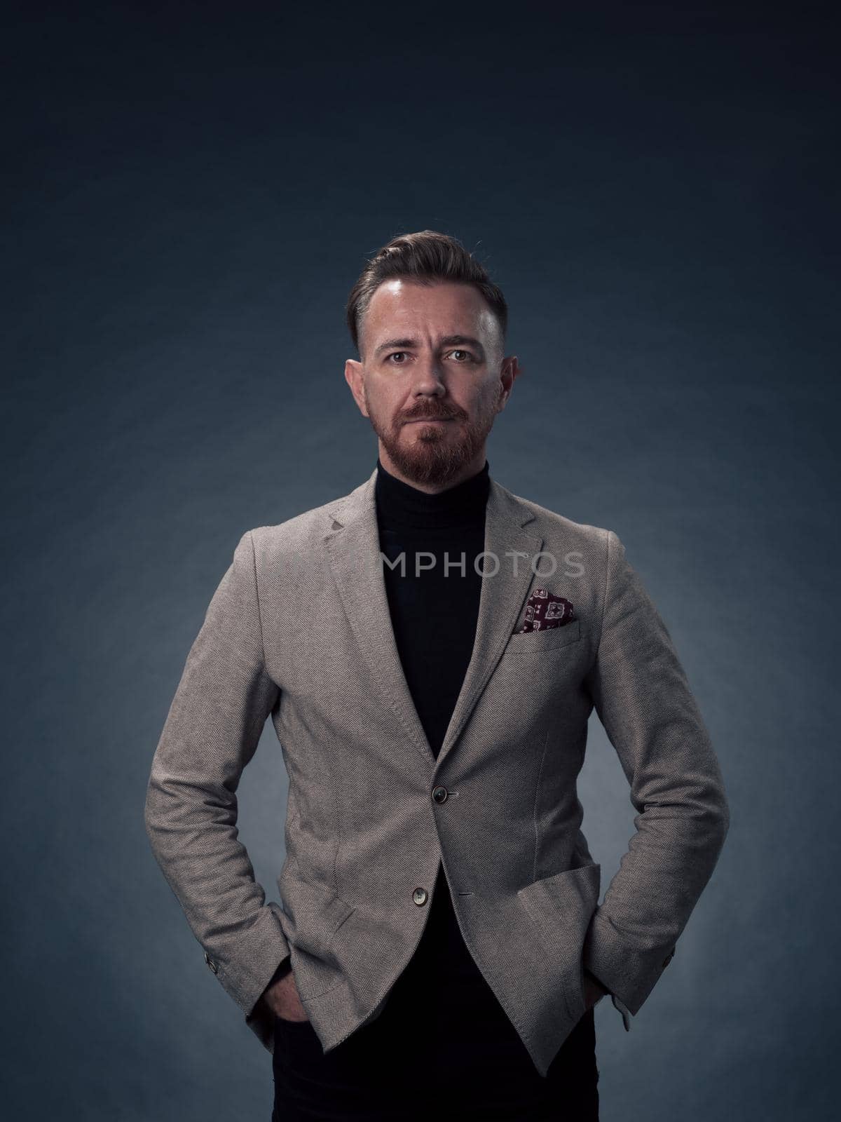 Portrait of a successful stylish elegant senior businessman with a grey beard and casual business clothes confident in photo studio isolated on dark background gesturing with hands. High-quality photo