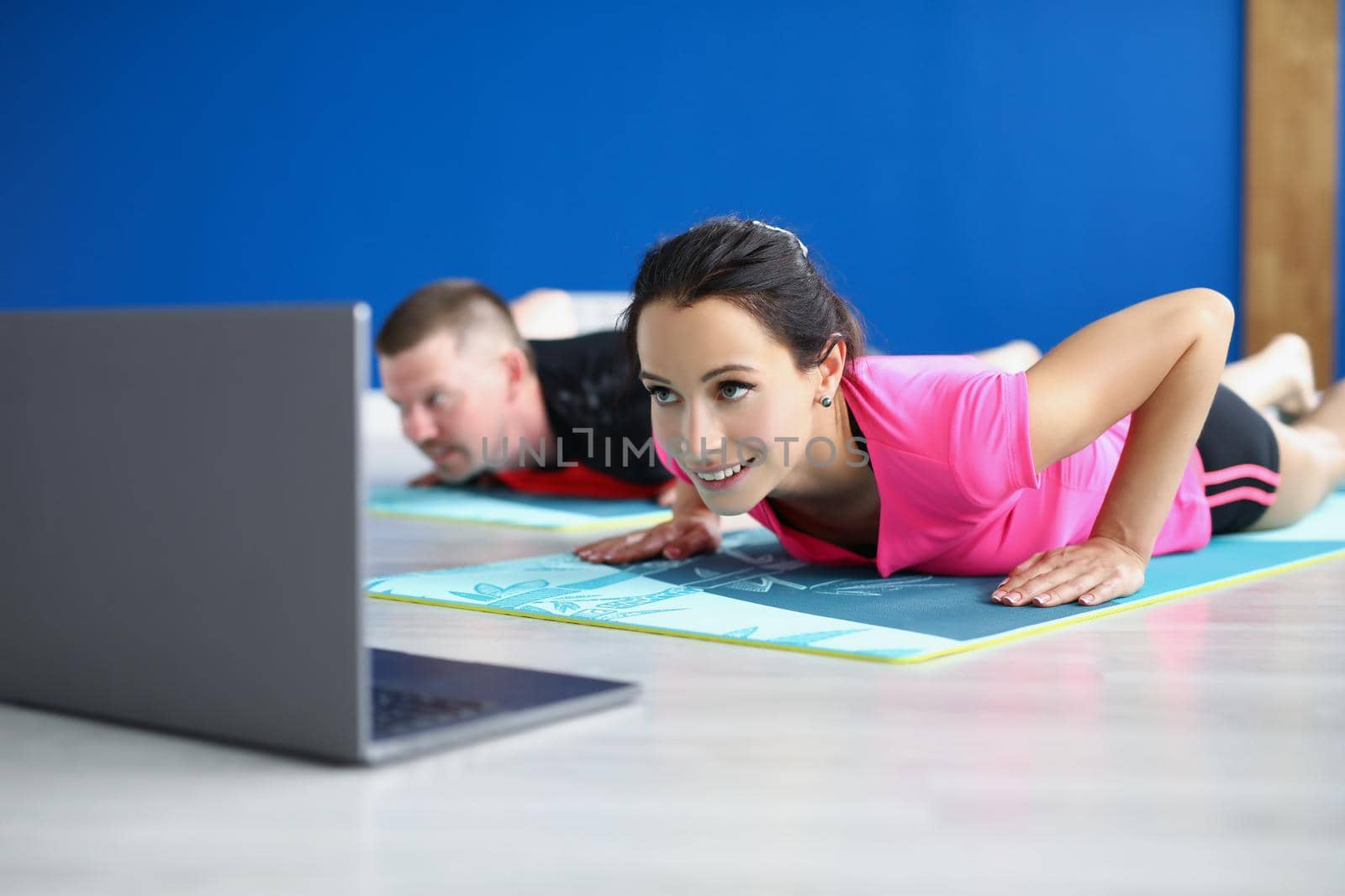 Low angle of woman and man practicing yoga in studio, perform asana on mat. Morning ritual for body and soul health. Active lifestyle, hobby, habit concept