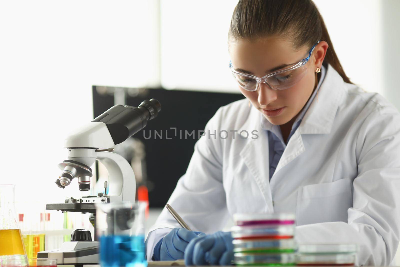 Portrait of concentrated chemist worker write down thoughts on investigation project in lab. Biologist examine samples in modern clinic. Science concept