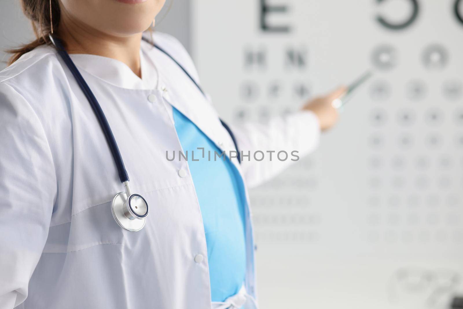 Close-up of female eye doctor point on letter on eye test chart. Optician in uniform, appointment in eye clinic. Checkup, health, ophthalmologist concept