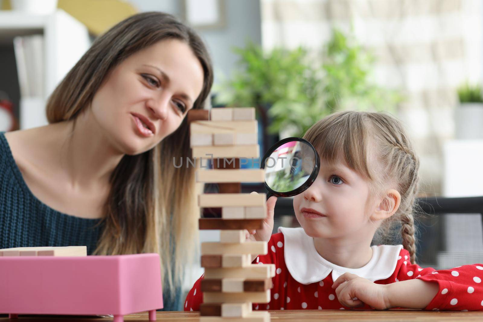 Cute little girl watch through magnifying glass on high wooden tower by kuprevich