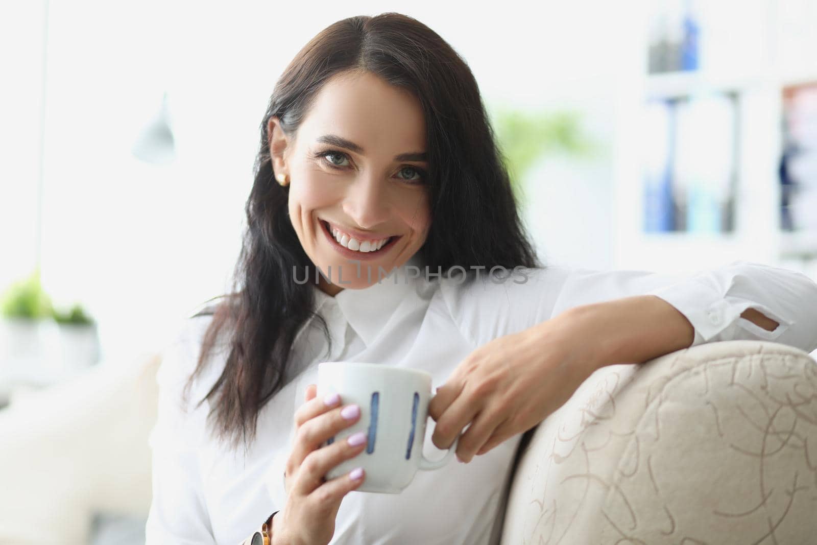 Beautiful brunette young woman chilling with cup of hot drink by kuprevich