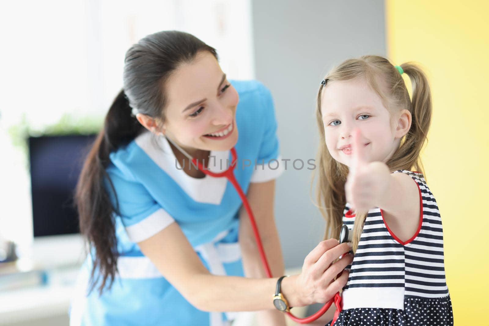 Girl being examined by pediatrician doctor, happy child show thumbs up gesture by kuprevich