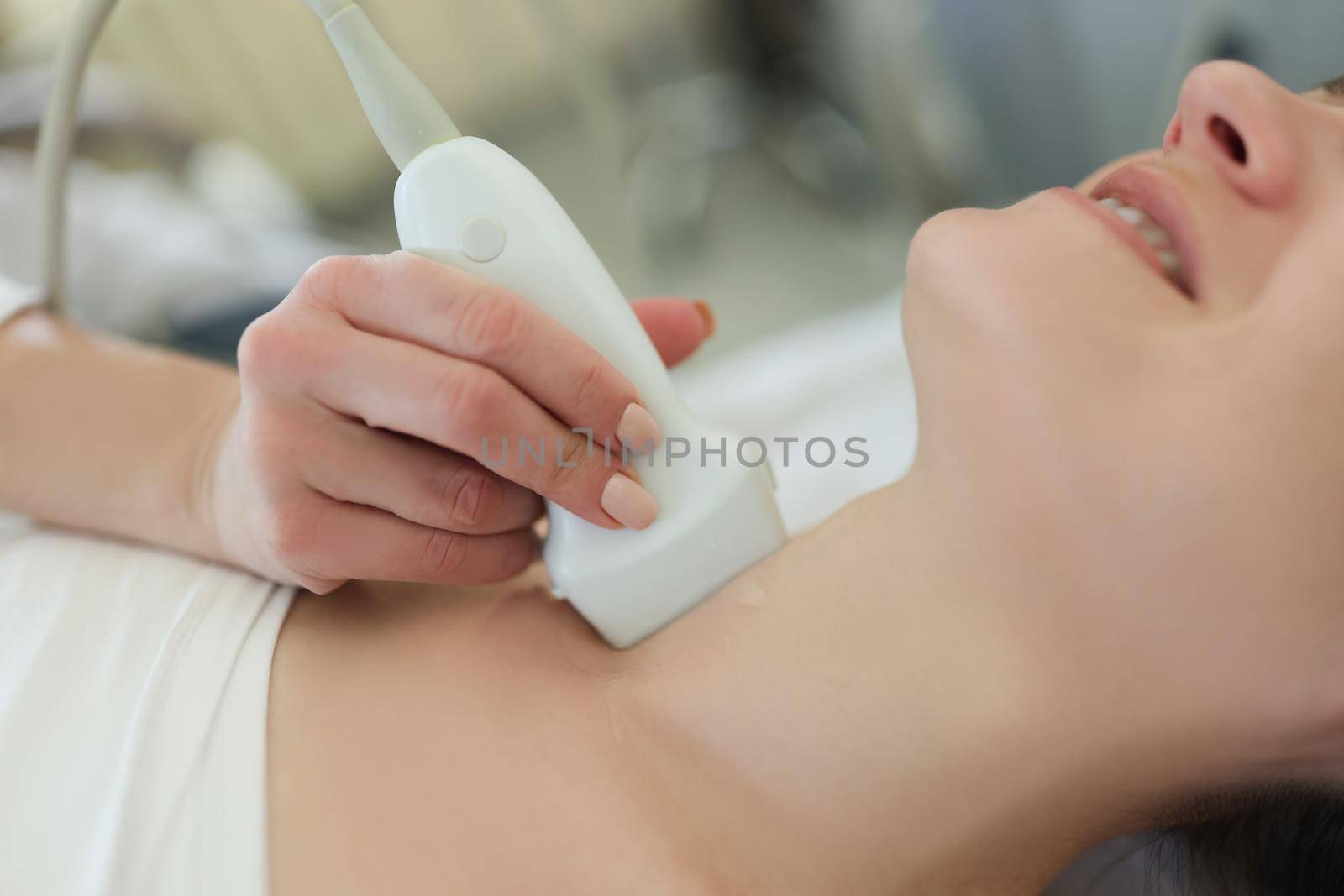 Close-up of ultrasound scanning diagnostic for woman of thyroid gland in hospital, doctor hold ultrasound sensor over neck. Diagnostics, healthcare concept