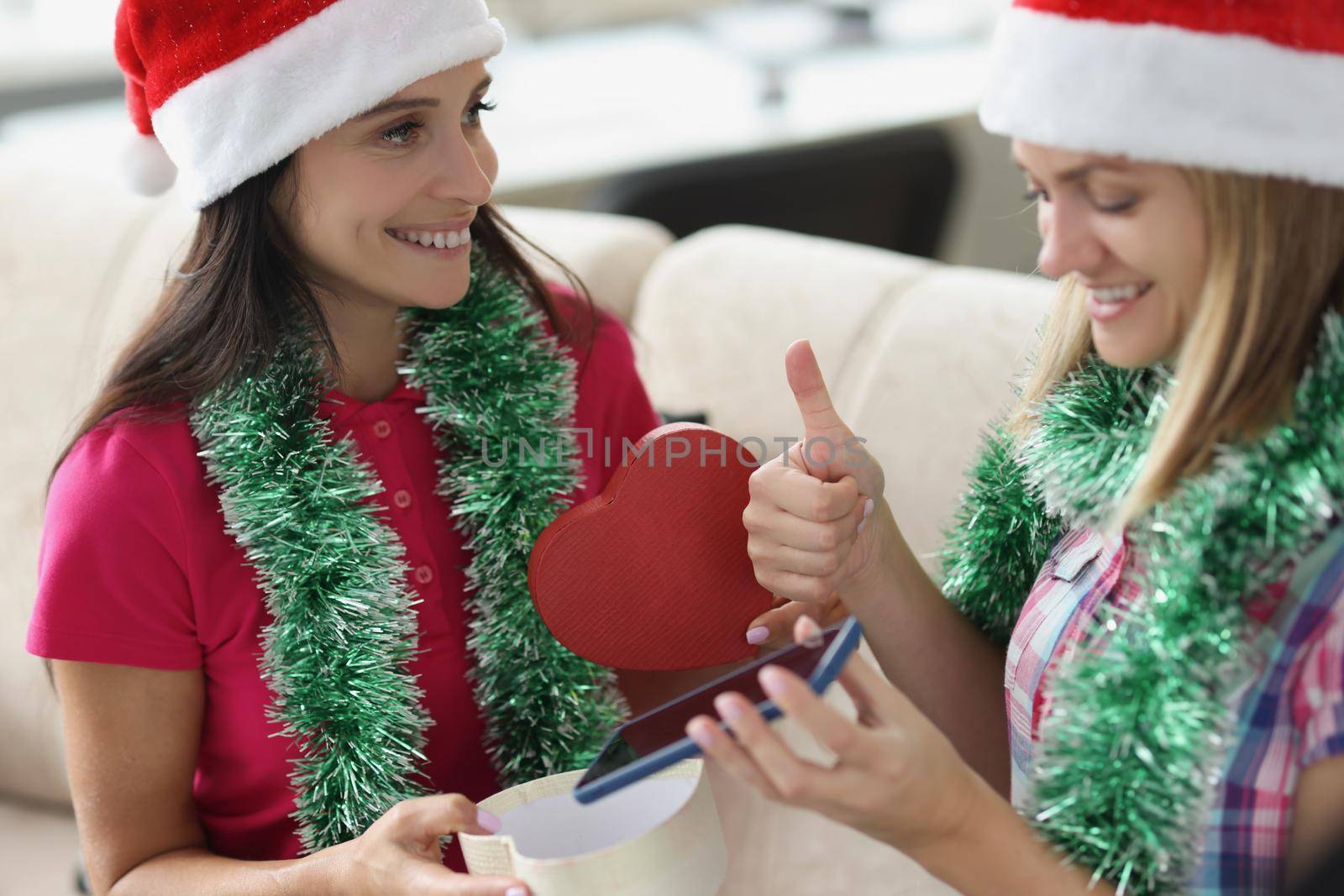 Portrait of woman receive present from sister in red box new model of smartphone. Festive mood and christmas outfit, celebrate new year. Holiday concept