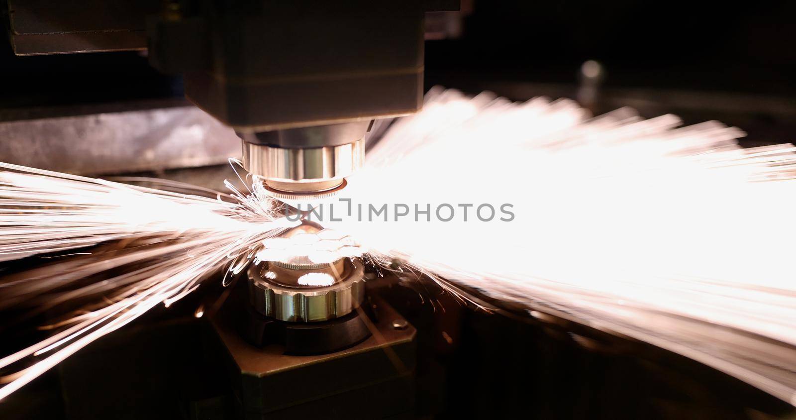 Close-up of neon sparks fly of machine head for metal processing laser metal. Cutting machine and metal plate. Manufacturing, production, factory concept