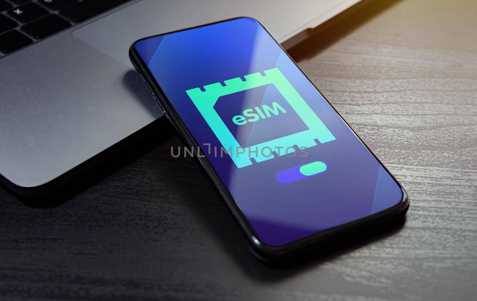 eSIM technology concept. Embedded SIM electronic phone sim card - mobile cellular global internet communication technology. Close up smartphone lying on a wooden table with an esim icon on the screen.