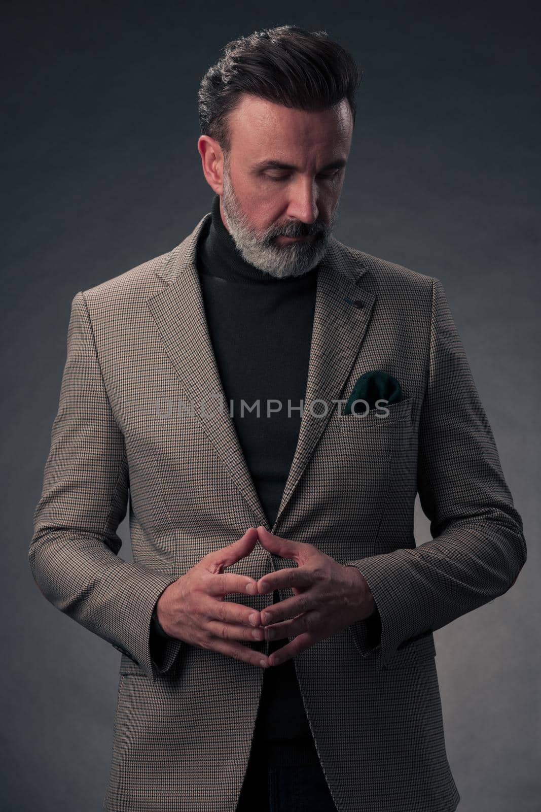 Portrait of a stylish elegant senior businessman with a beard and casual business clothes in photo studio isolated on dark background gesturing with hands by dotshock