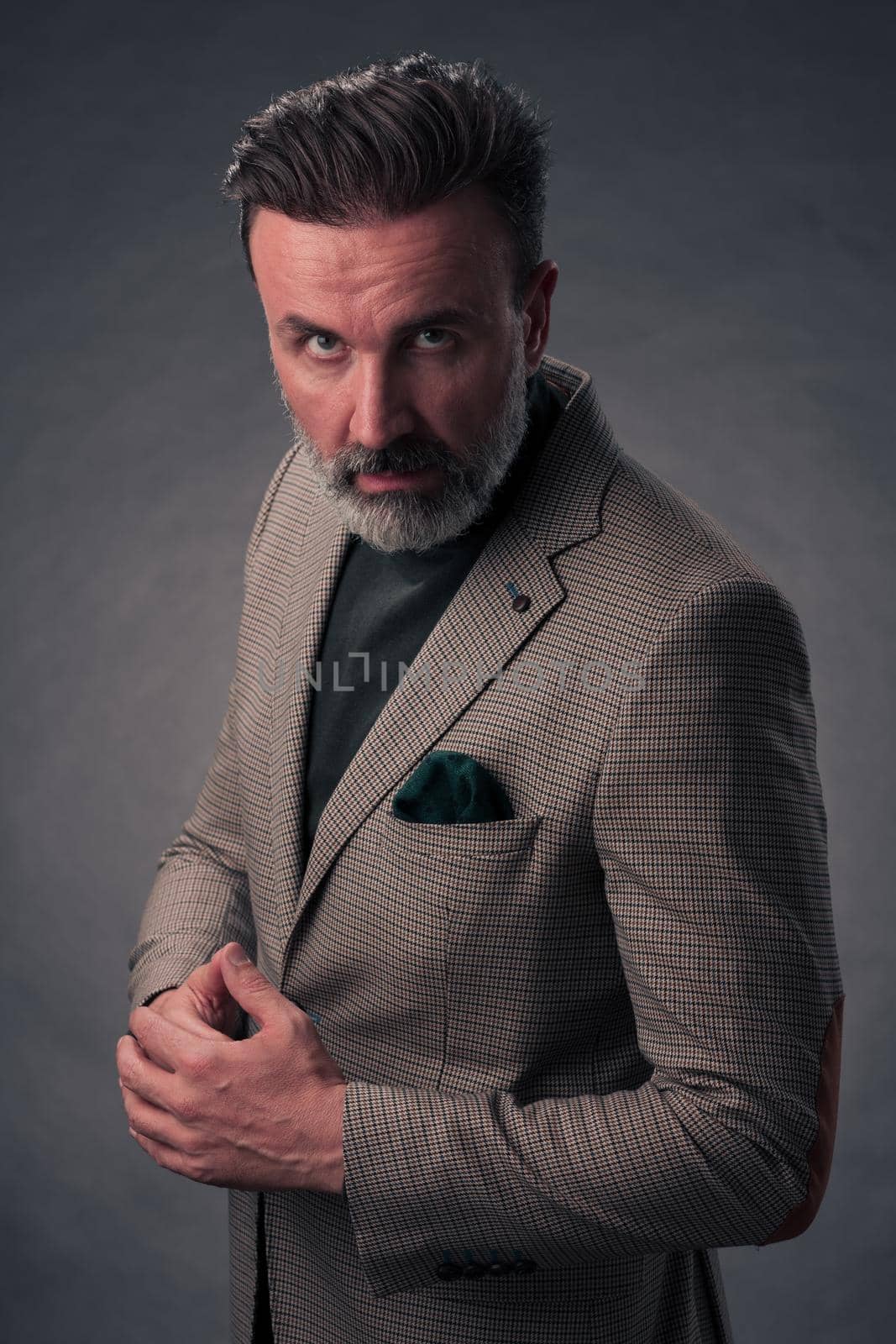 Portrait of a stylish elegant senior businessman with a beard and casual business clothes in photo studio isolated on dark background gesturing with hands by dotshock