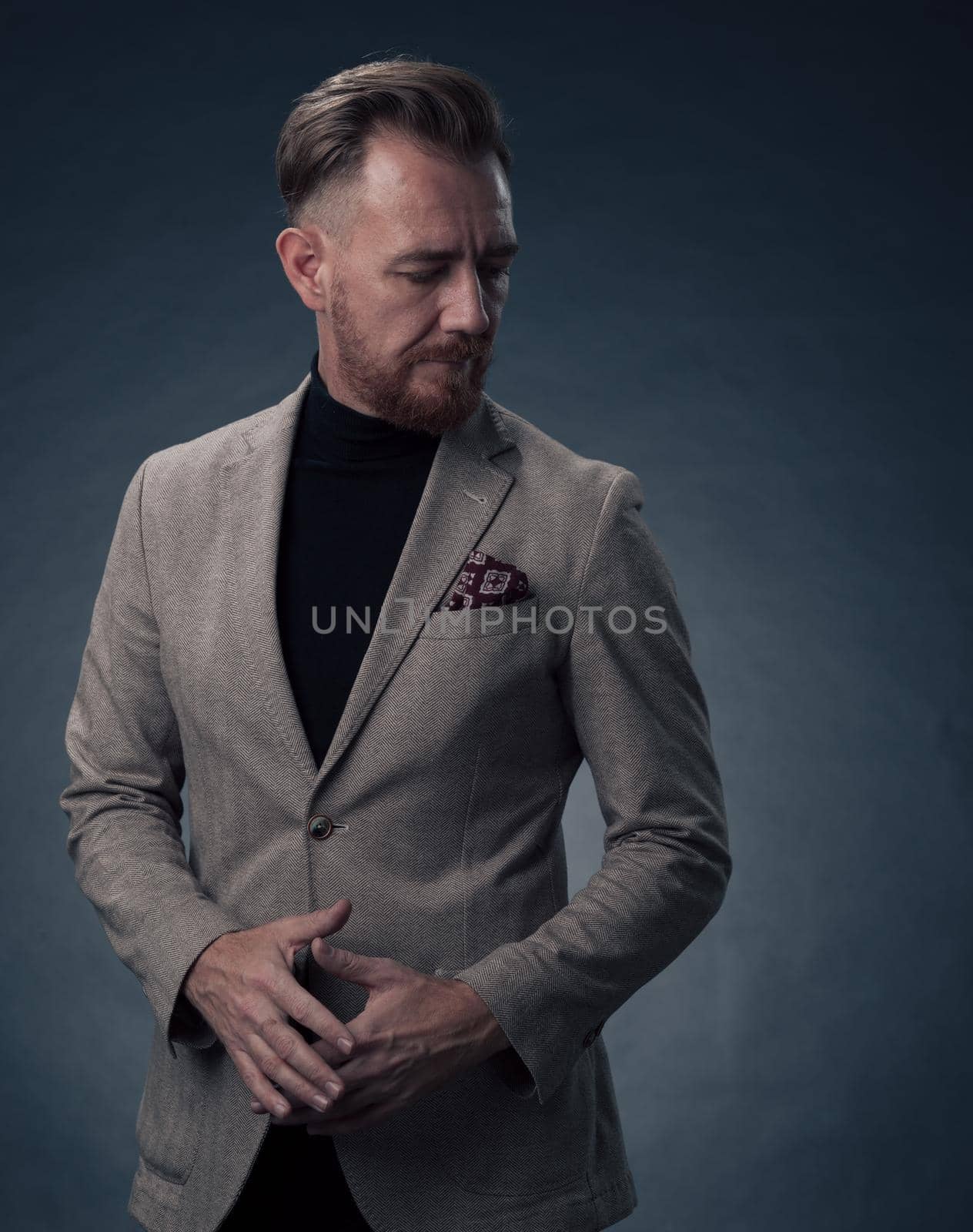 Portrait of a successful stylish elegant senior businessman with a grey beard and casual business clothes confident in photo studio isolated on dark background gesturing with hands. High-quality photo