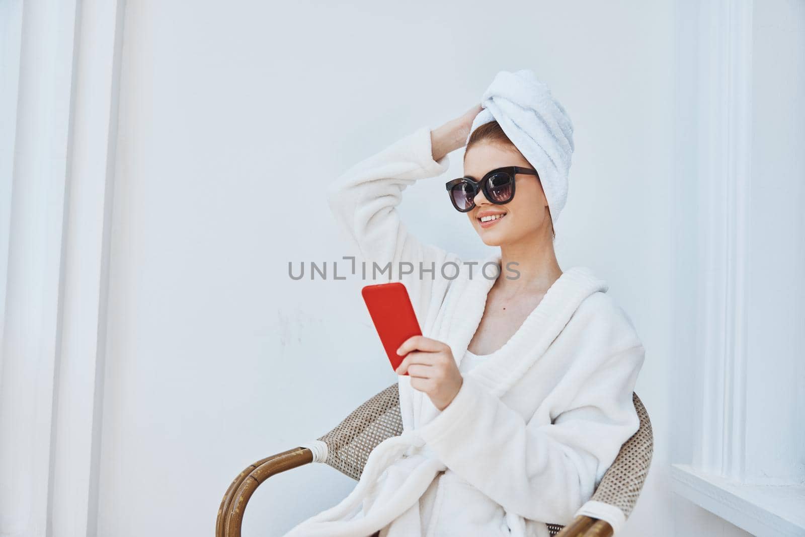 cheerful woman uses a red phone in a chair in a white robe by SHOTPRIME